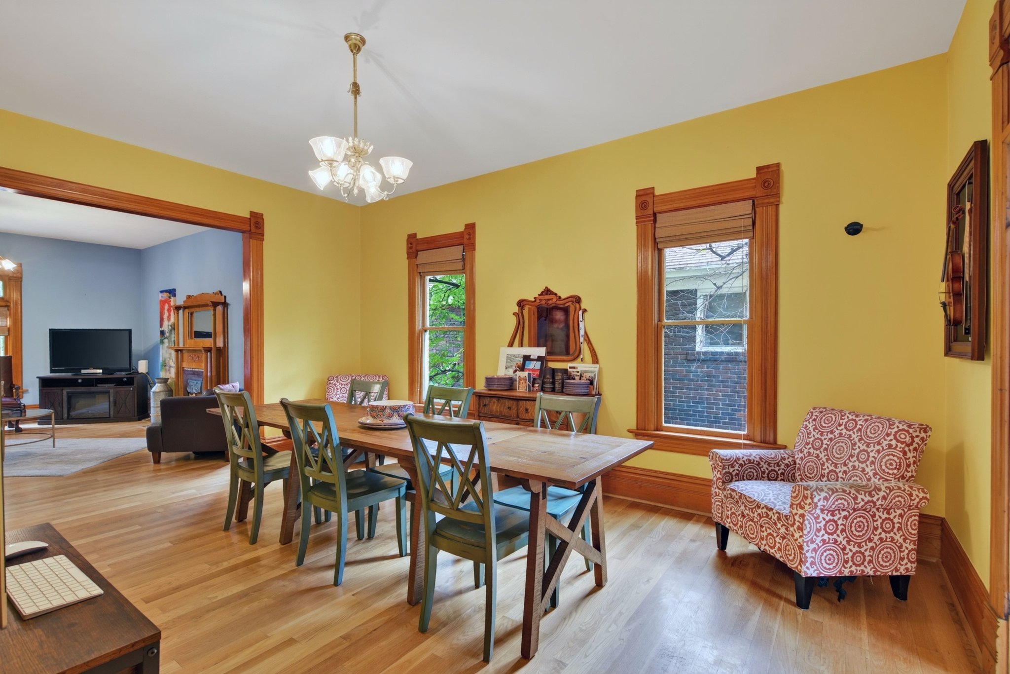 Spacious dining area featuring wood-finish flooring, a chandelier, and two windows with wood trim