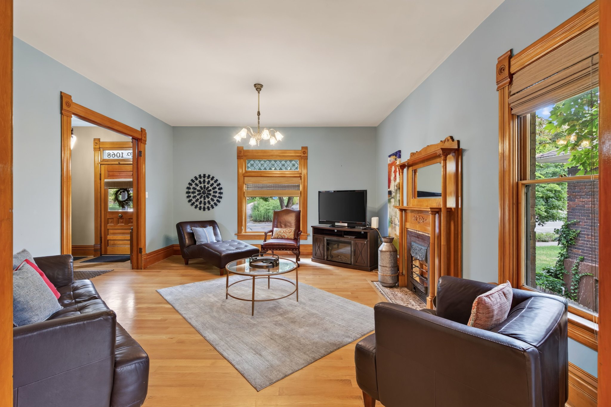Spacious interior featuring hardwood flooring, light blue wall tones, and extensive natural wood trim and window casings