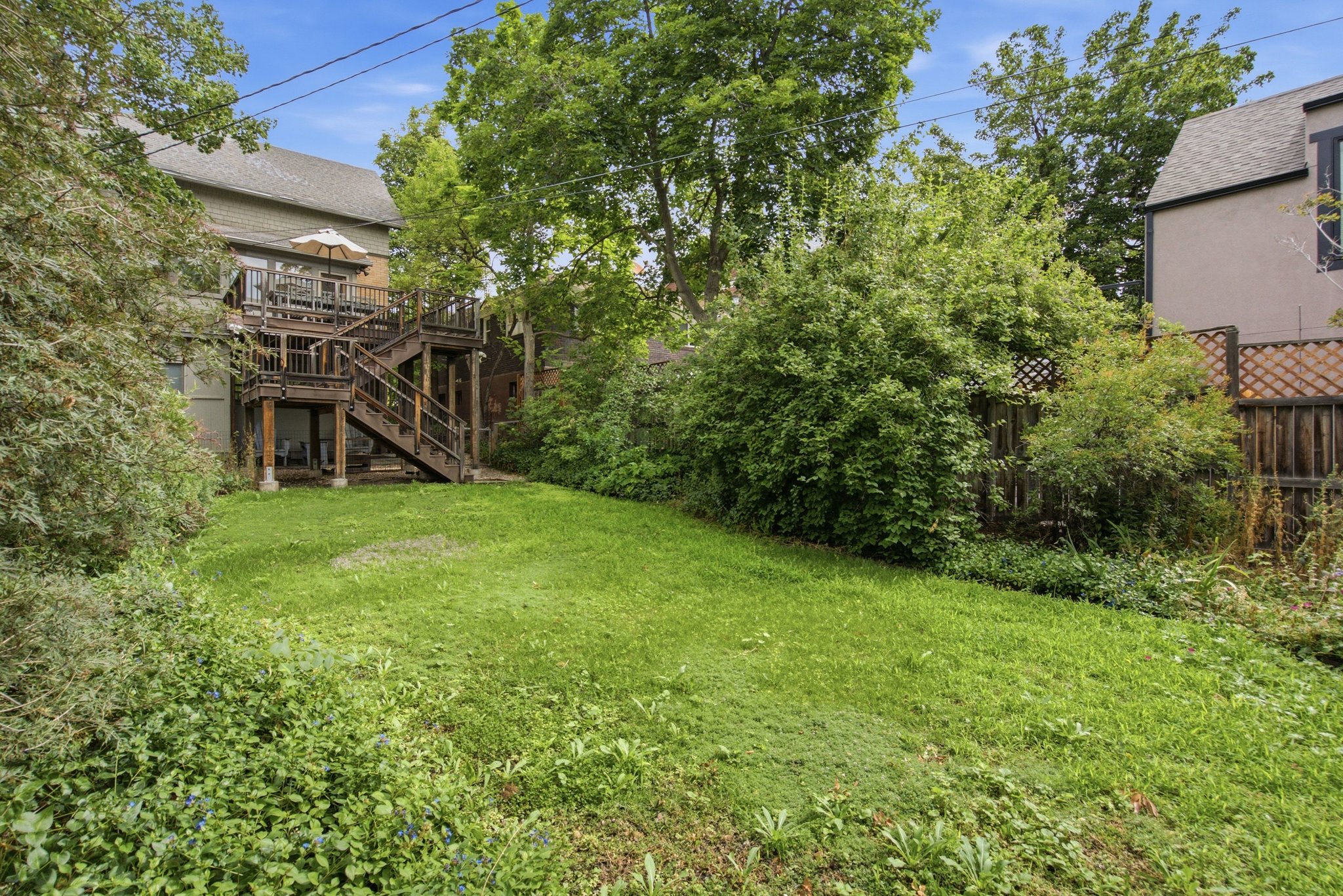 Expansive green lawn framed by mature trees and shrubs