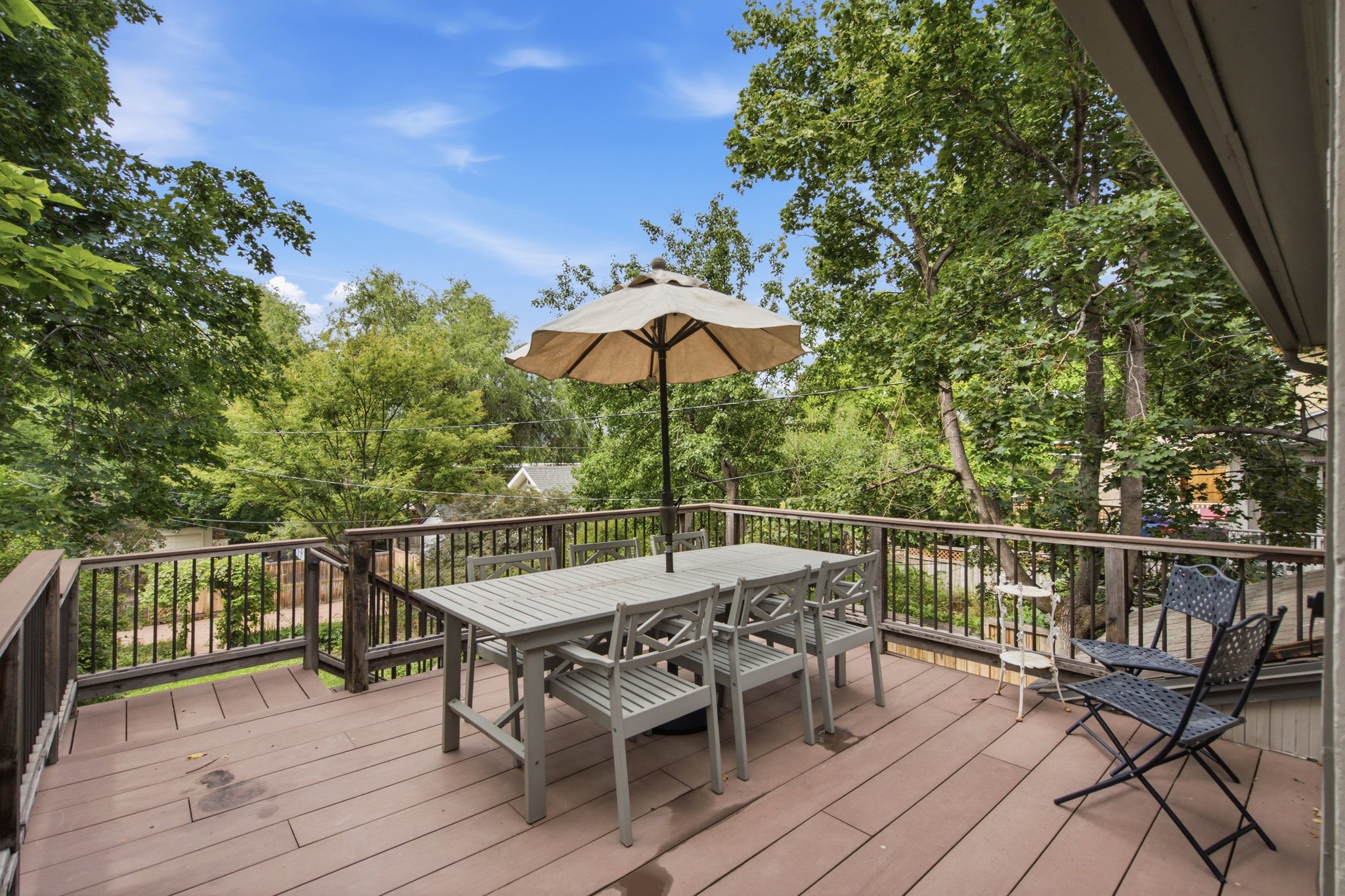 Spacious outdoor deck featuring brown wood-finish flooring and dark wood railings