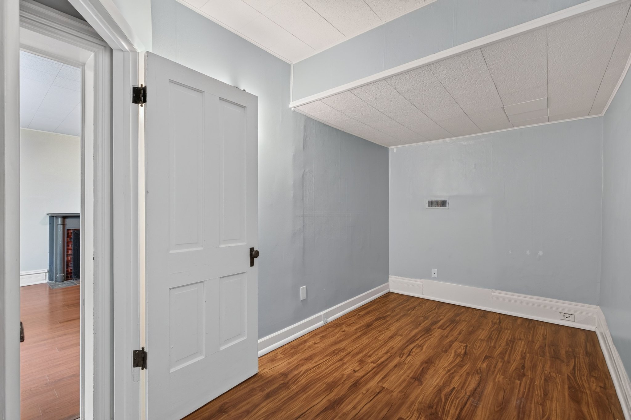 Interior room featuring wood-finish flooring, light blue walls, and a white paneled door