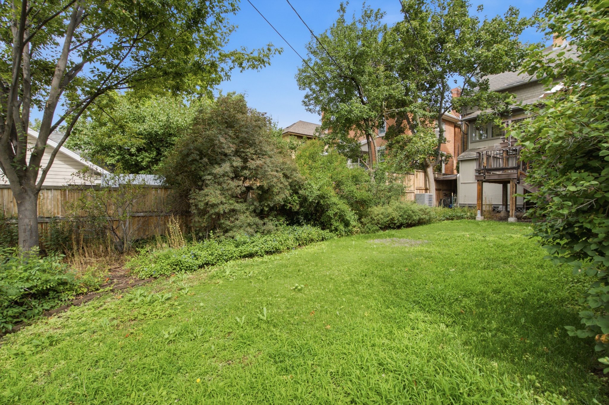 Expansive green lawn with mature trees and established perimeter landscaping