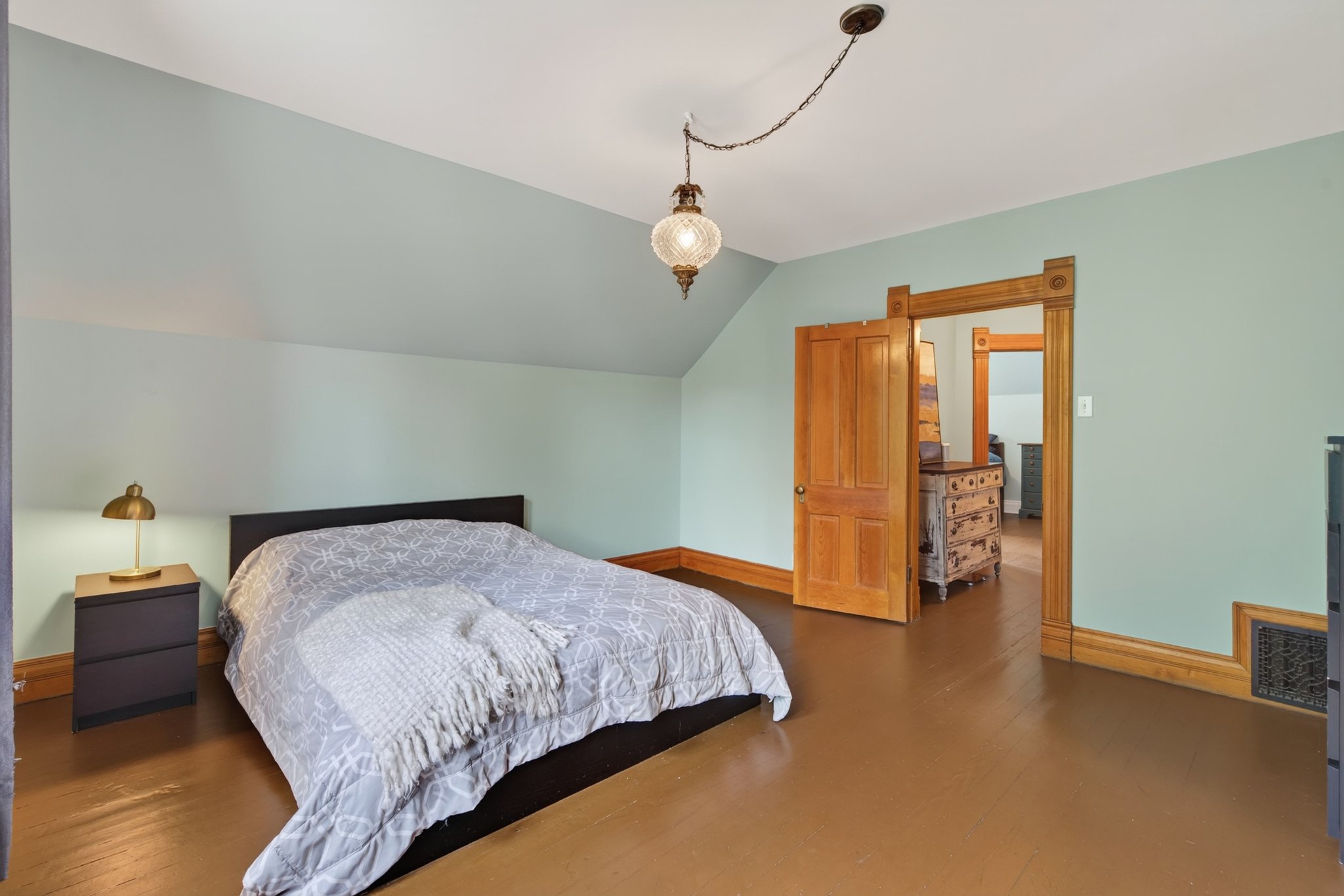 Sloped ceiling bedroom featuring warm wood-finish flooring