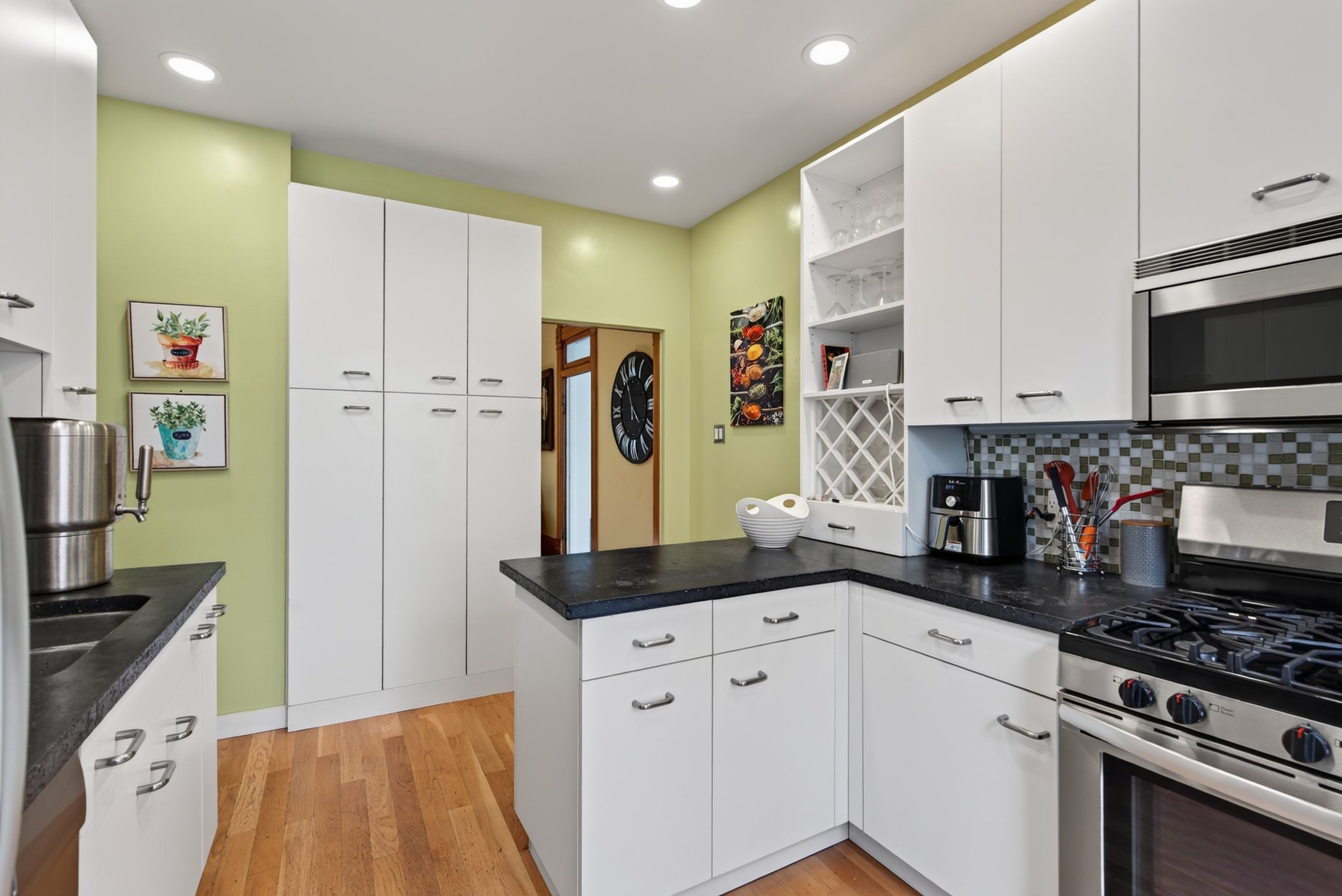 Kitchen featuring white cabinetry with brushed nickel hardware, dark countertops, and wood-finish flooring