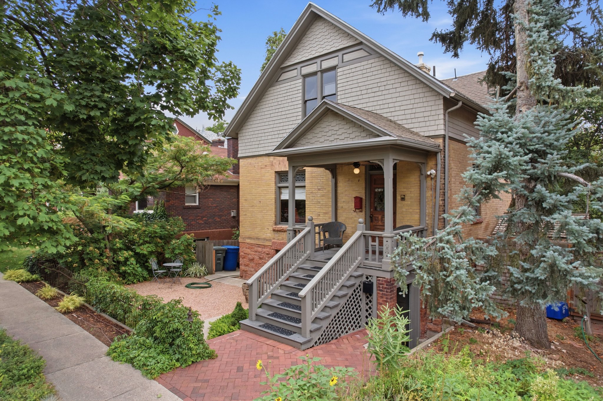 Two-story brick and shingle exterior featuring a covered porch with decorative railings