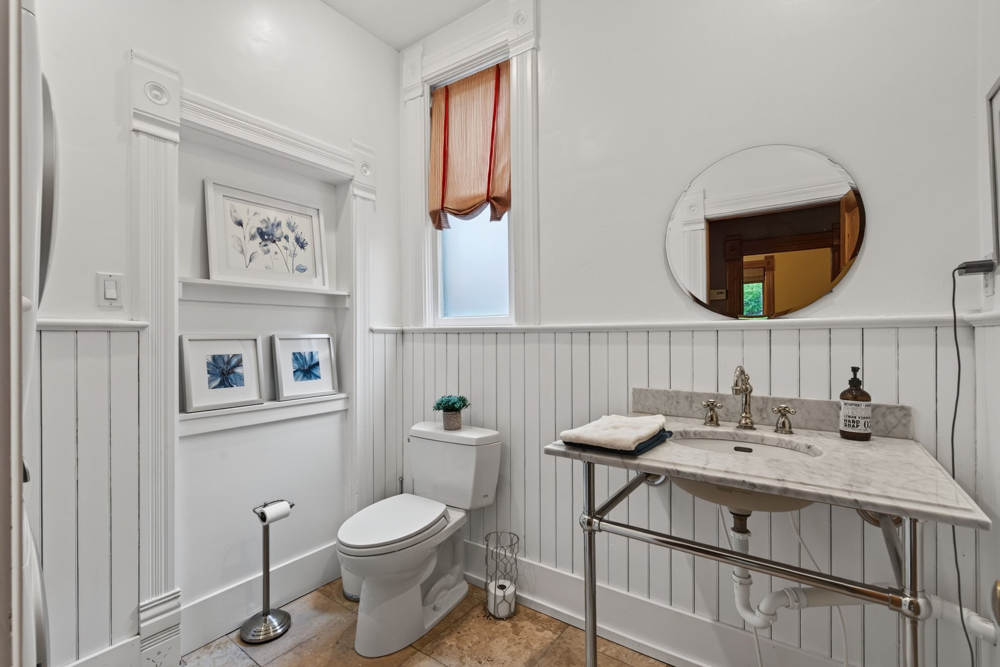 Bathroom featuring wainscoting, an integrated sink with a stone countertop, and a wall-mounted mirror