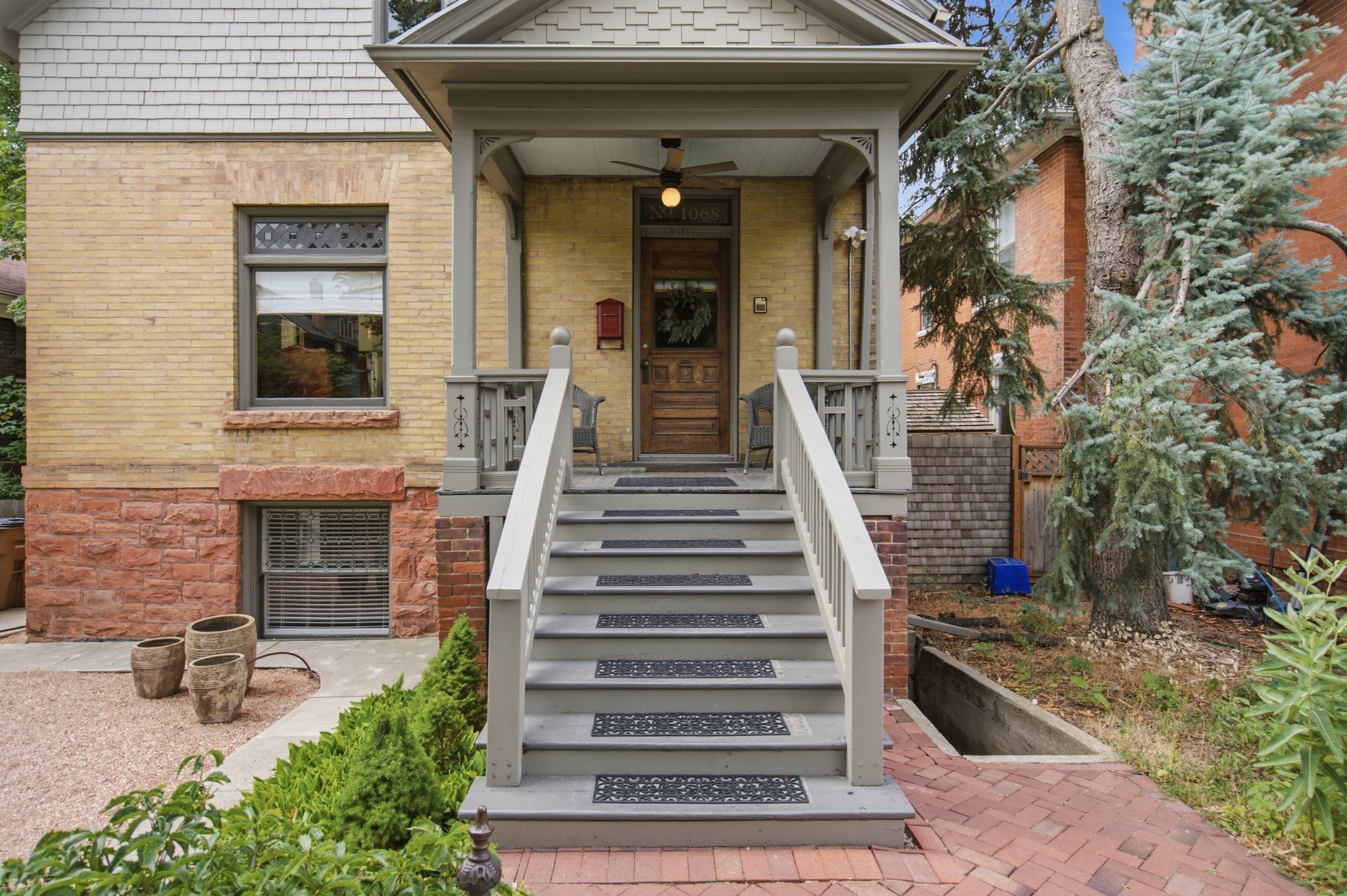 Inviting front entrance featuring a covered porch with decorative railings, a solid wood front door, and a brick walkway