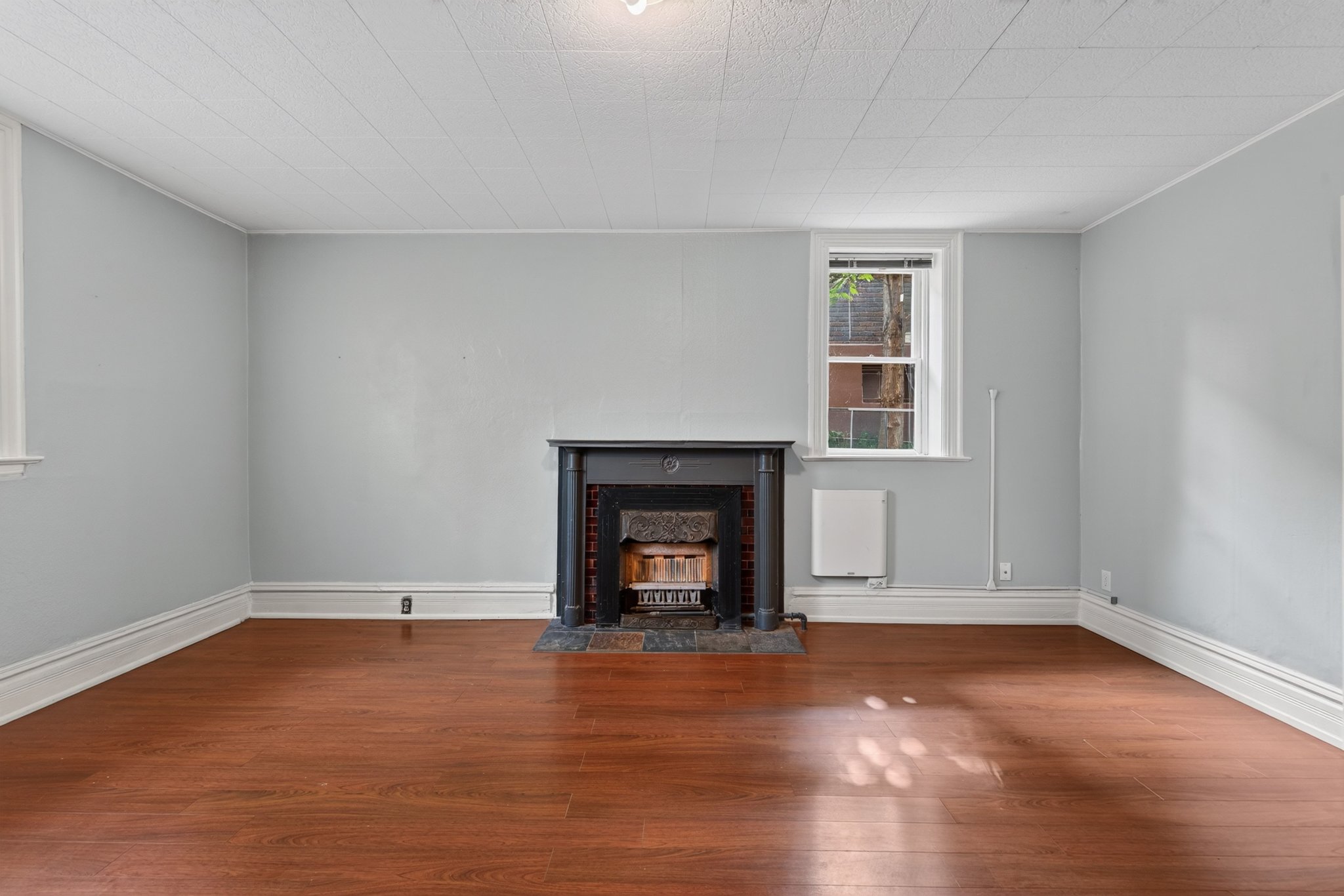Living area featuring a black fireplace with a marble hearth, wood-finish flooring, light blue walls, and white trim