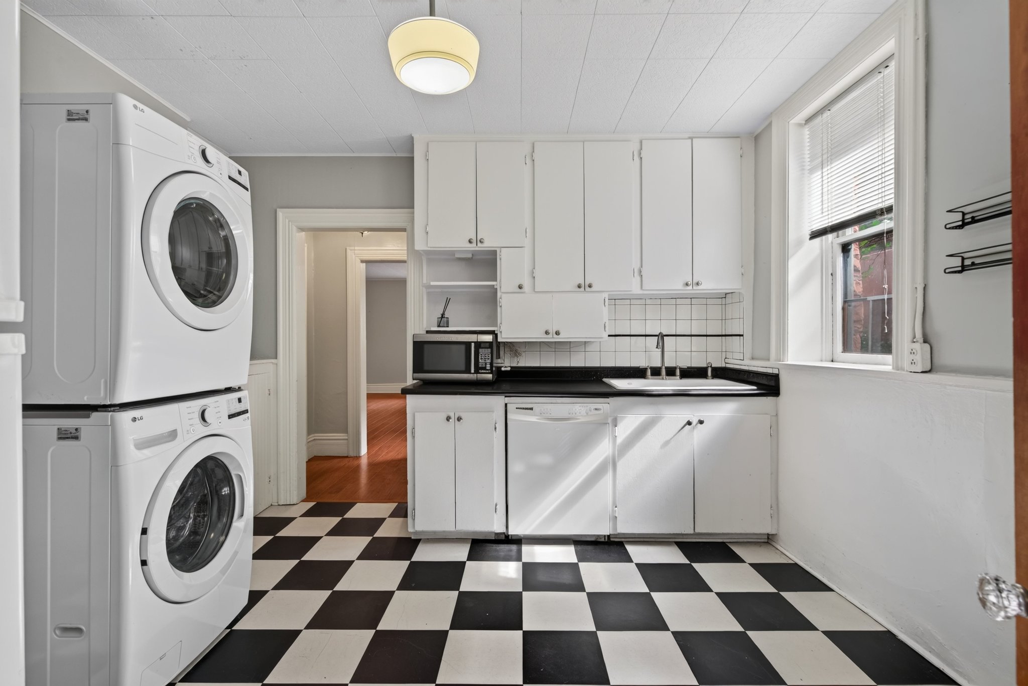 Kitchen with white cabinetry, black countertops, and a white tile backsplash
