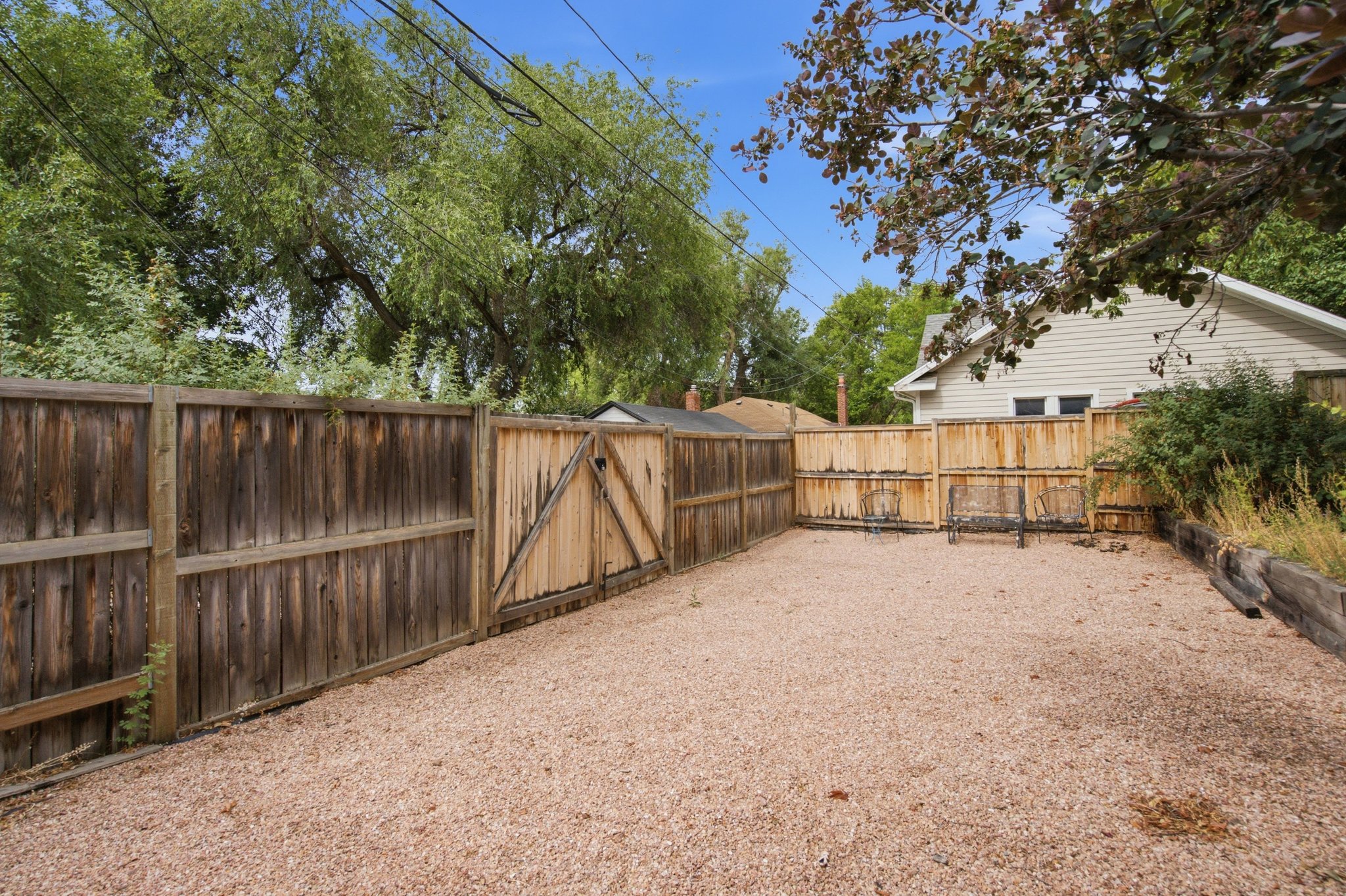 Gravel-covered outdoor area enclosed by wood fencing