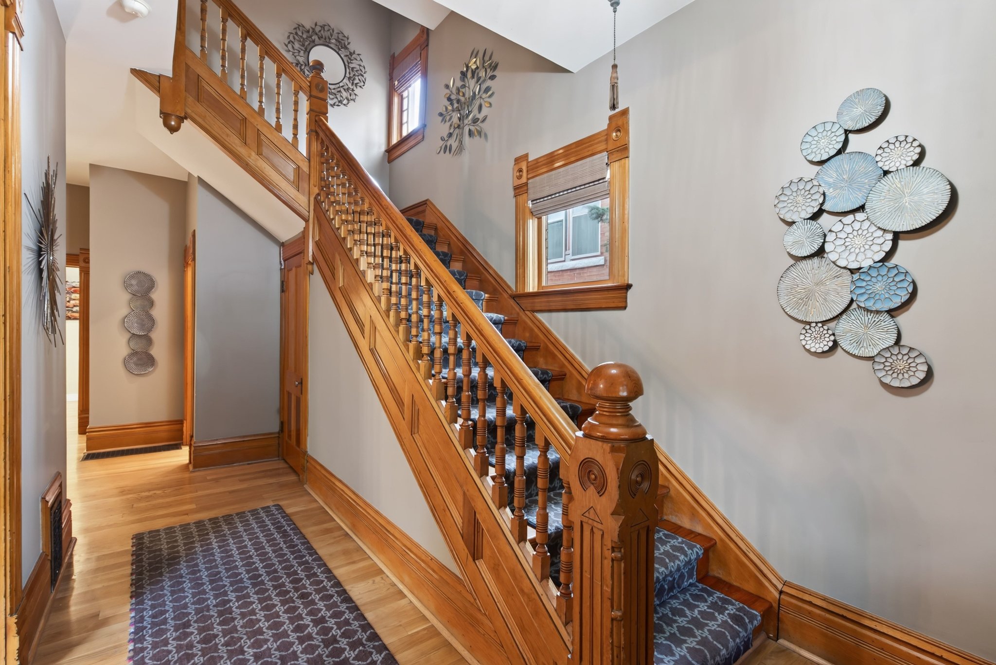 Hardwood staircase featuring ornate balusters and a patterned runner