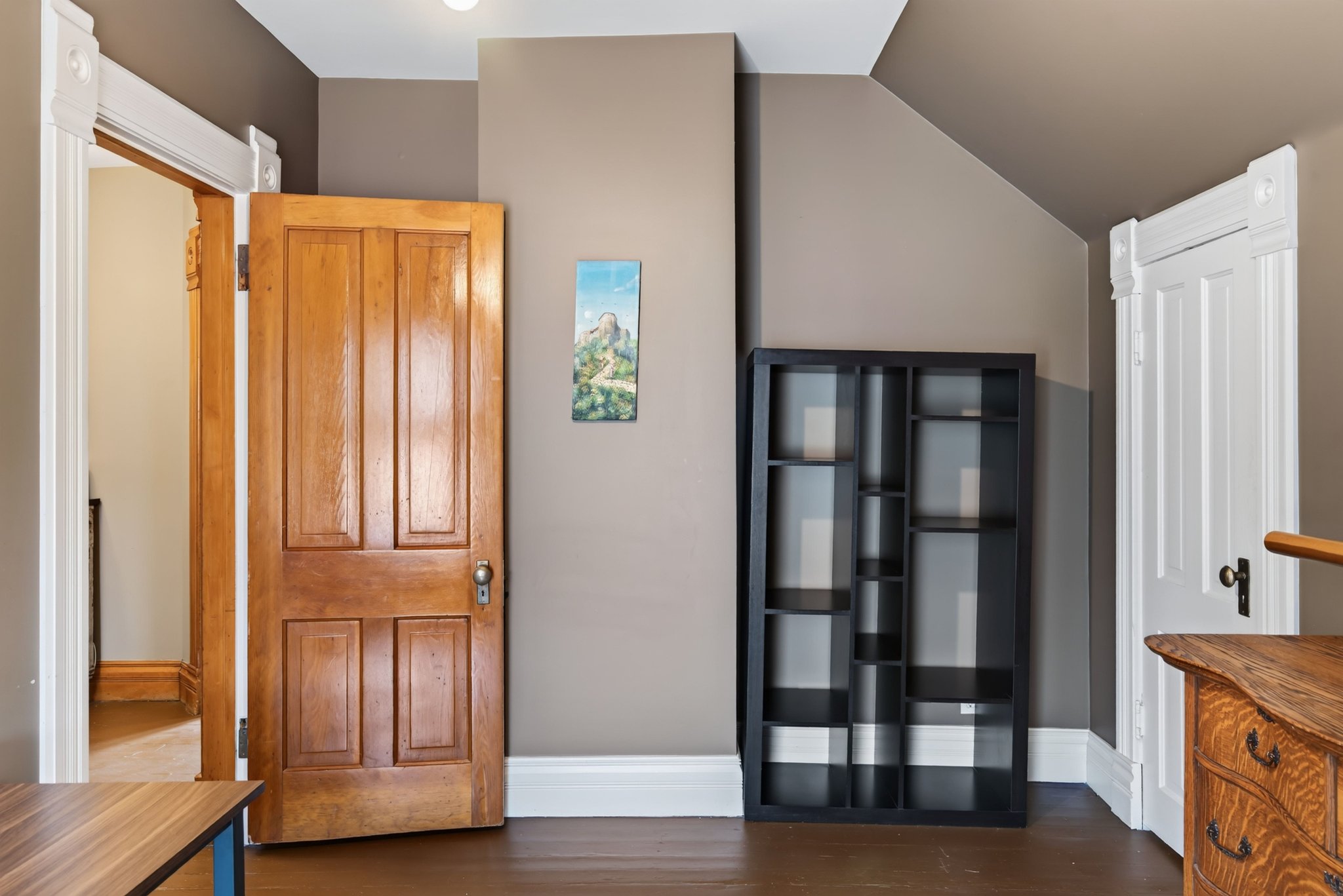 Natural wood-finish interior door with panel detailing and decorative white trim