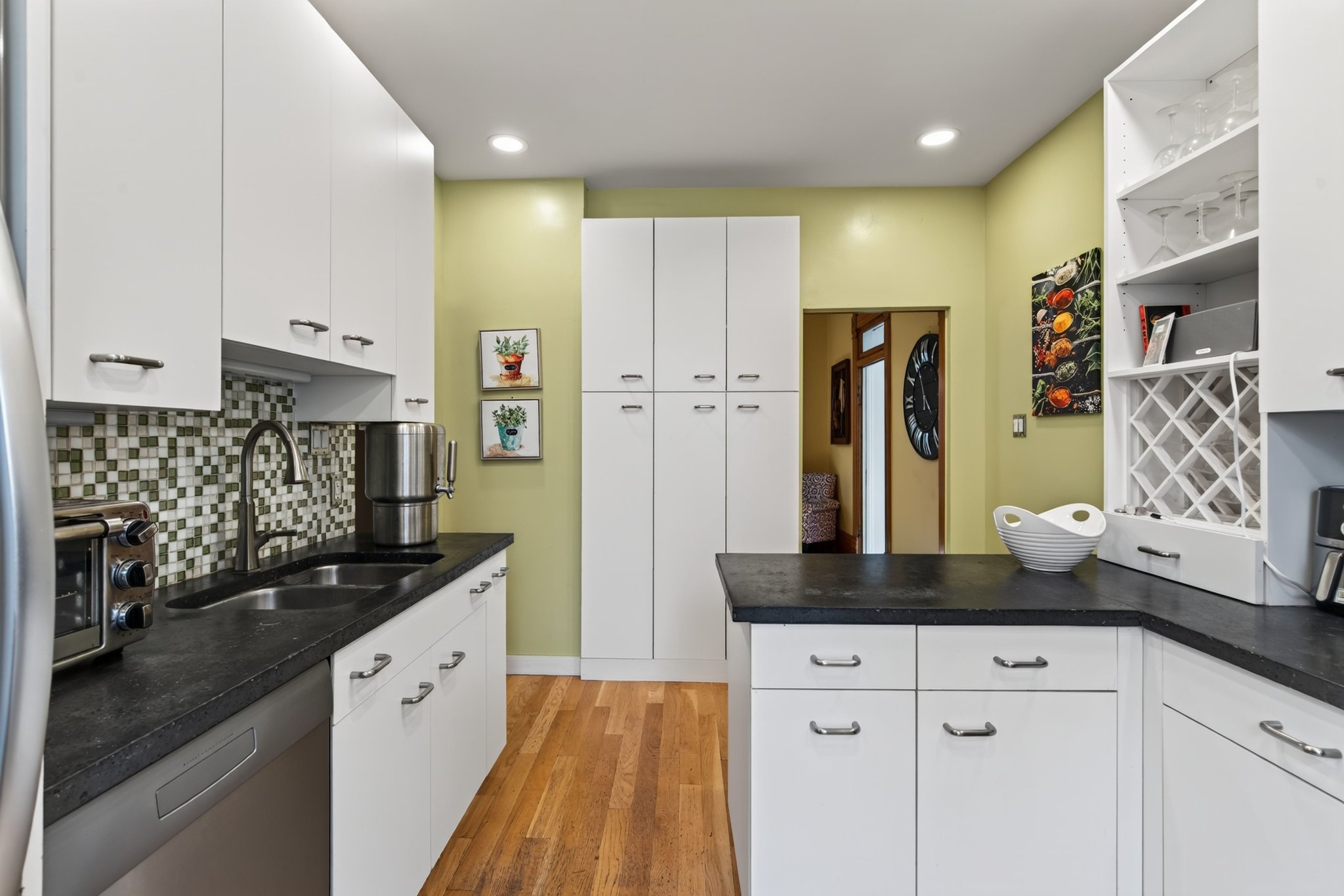 Modern kitchen featuring white cabinetry, dark countertops, a mosaic tile backsplash, wood-finish flooring, and recessed lighting