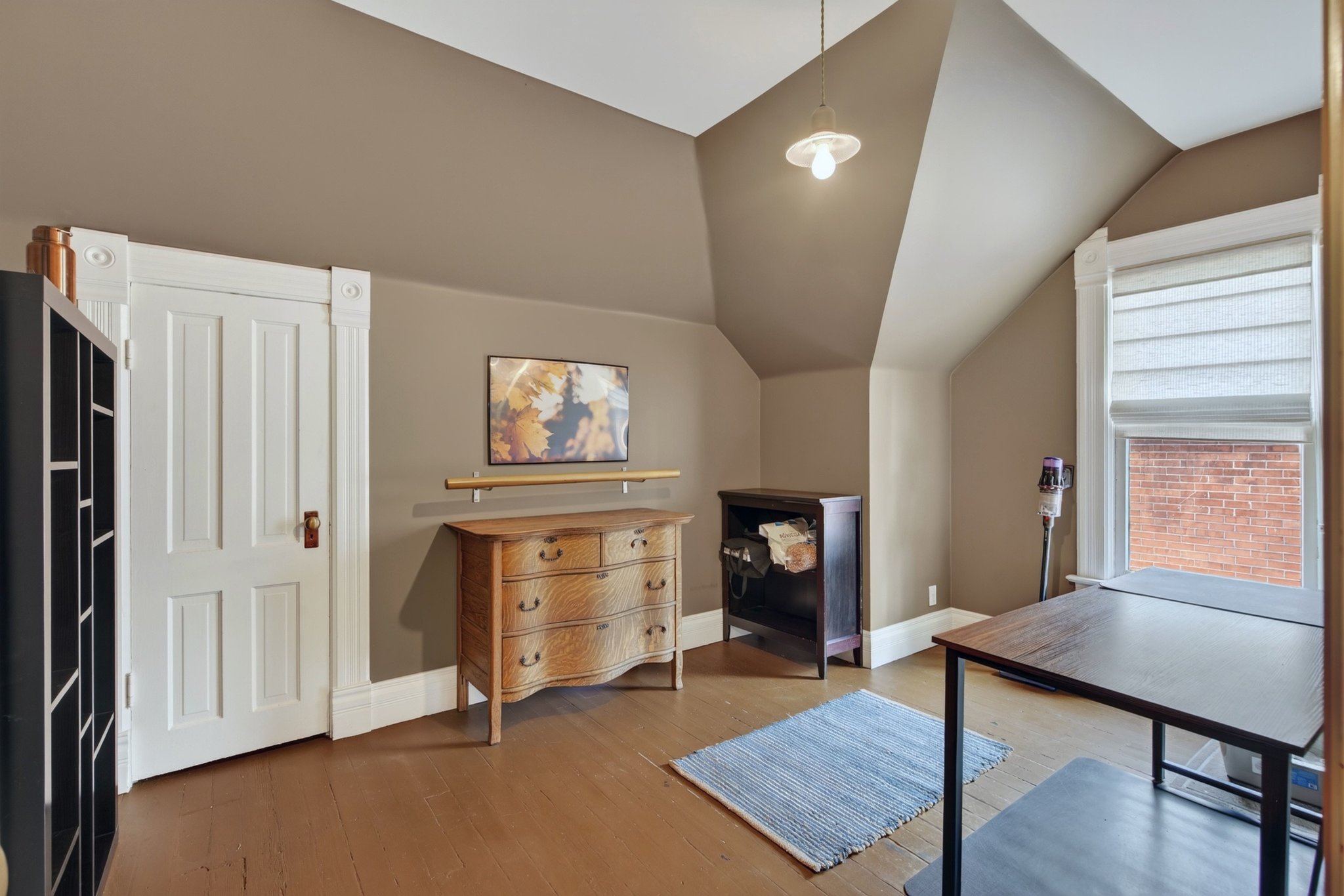 Room featuring wood-finish flooring, painted walls, and an angled ceiling