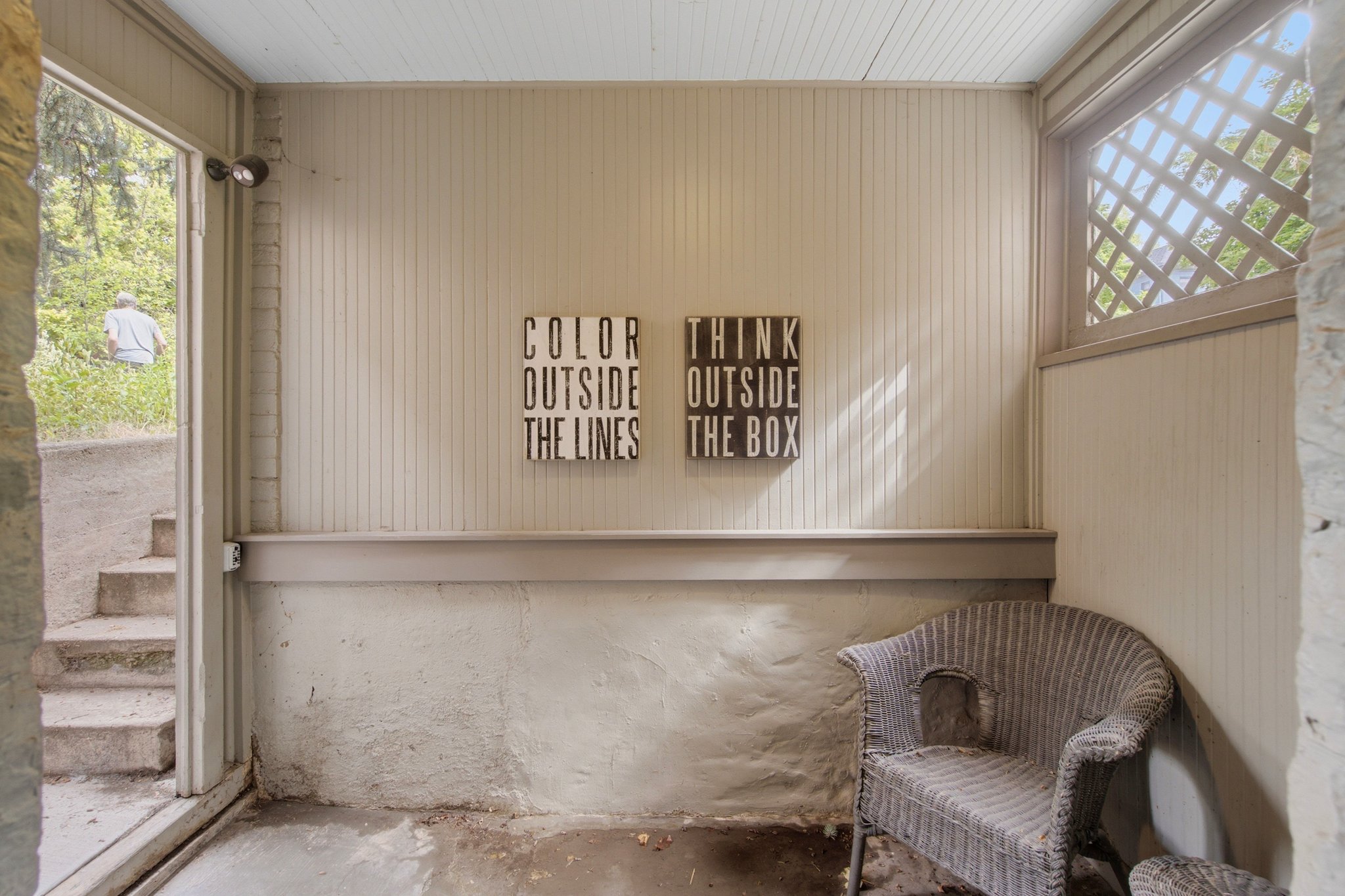 Enclosed patio area featuring vertical paneling, a lattice window detail, a light-colored ceiling, and concrete flooring