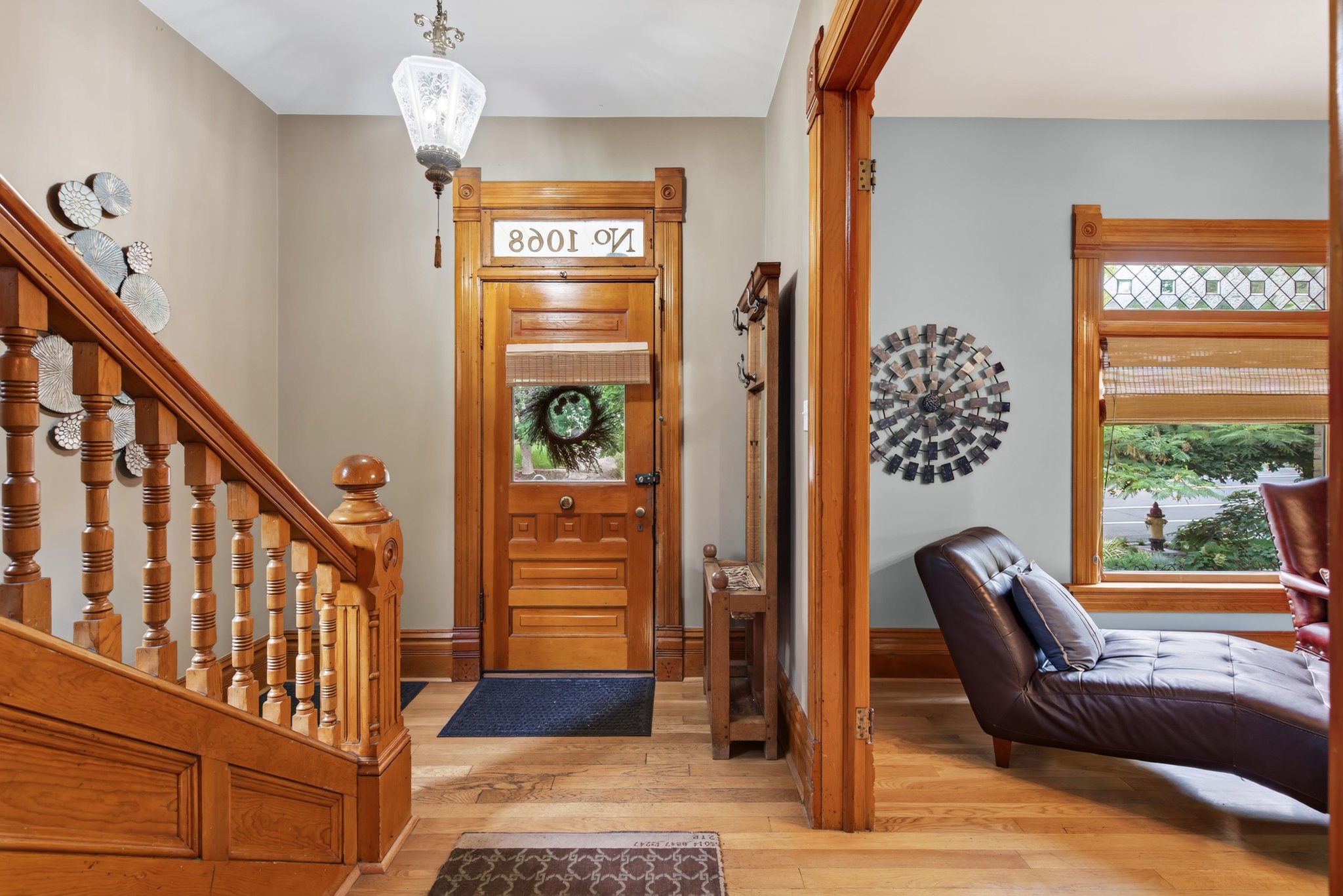 Entryway featuring wood-finish flooring, a detailed wooden staircase, and a solid wood front door with a glass insert