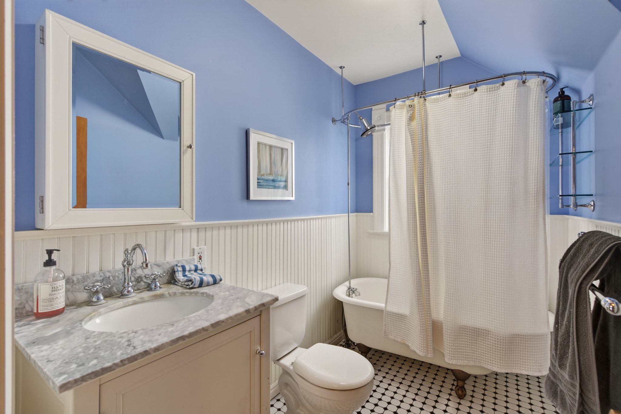 Bathroom featuring a clawfoot tub, white beadboard wainscoting, and a single vanity with a stone countertop
