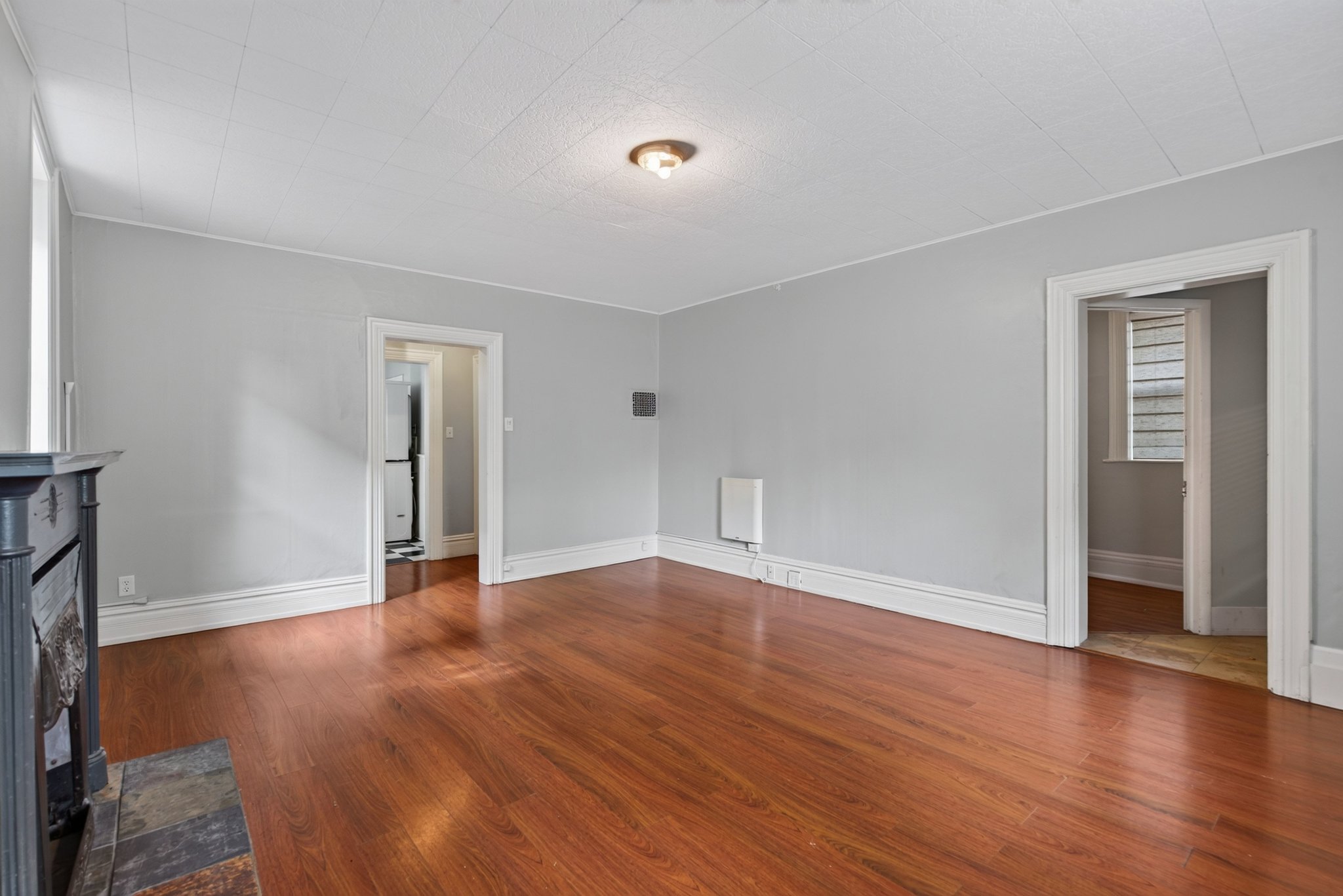 Spacious room featuring wood-finish flooring, light grey wall paint, and white baseboards