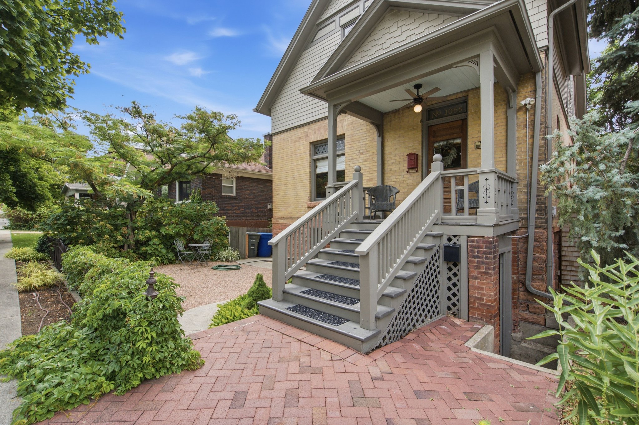 Brick exterior featuring a covered porch, decorative railing, and ceiling fan
