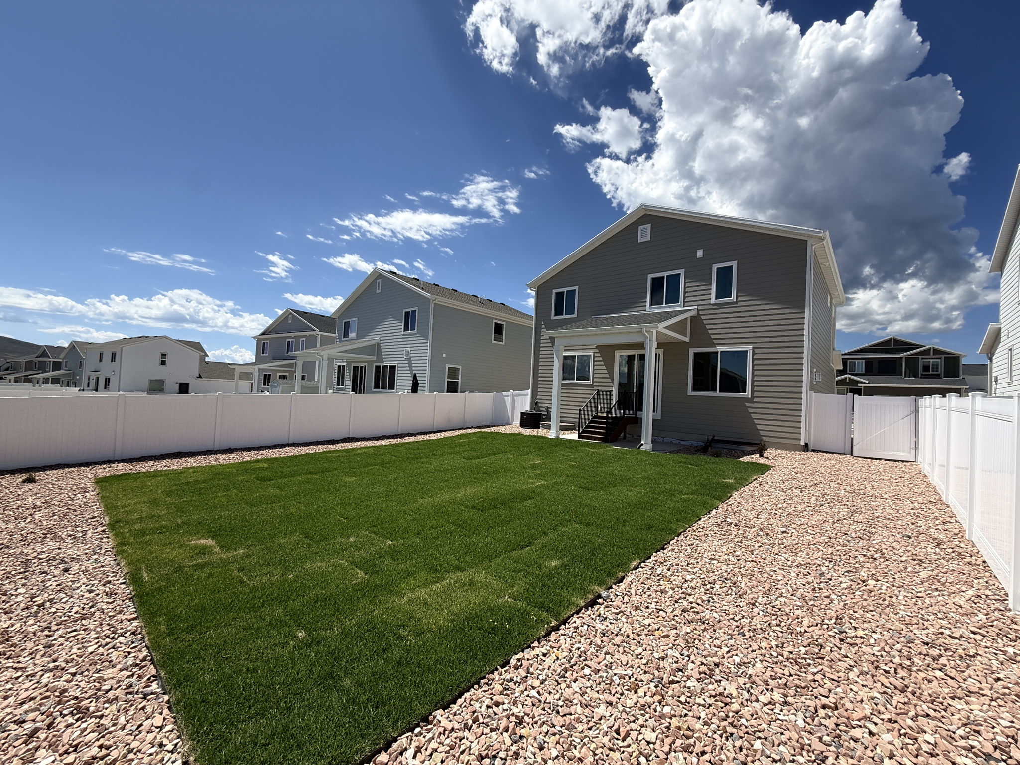 Expansive backyard featuring a new lawn, gravel perimeter, and full vinyl fencing