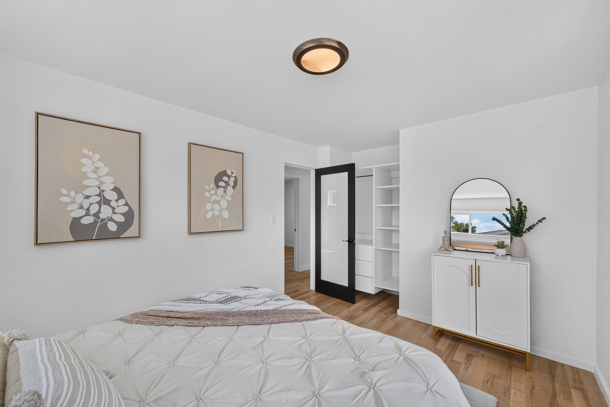 Bedroom featuring wood-finish flooring, a contemporary flush-mount ceiling light, and white walls