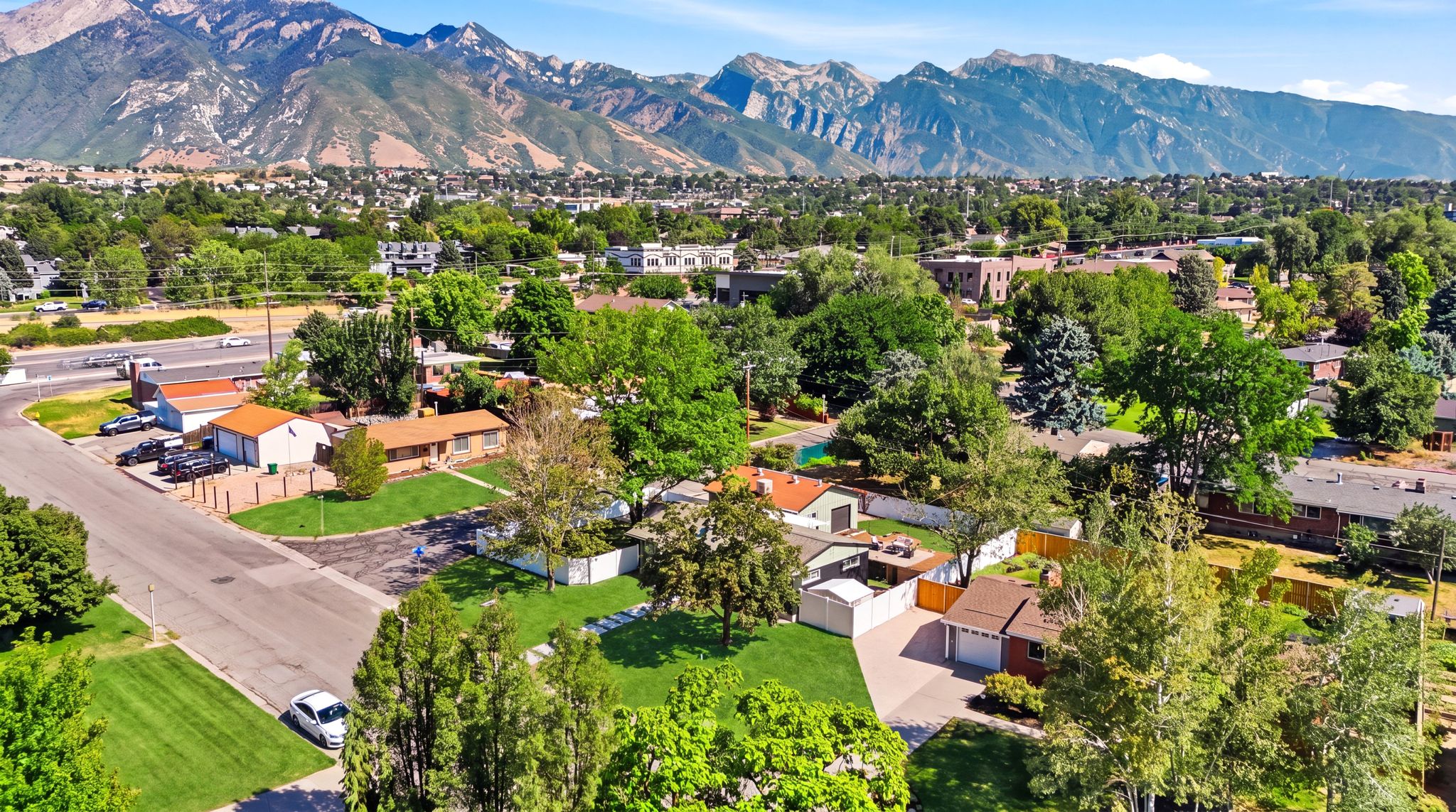 Residential neighborhood featuring mature trees, paved streets, and a mountainous backdrop