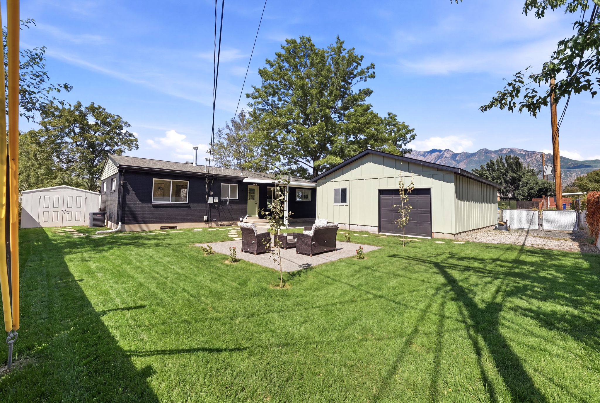 Spacious backyard featuring a large lawn, a detached storage shed, and a separate utility building with a roll-up door