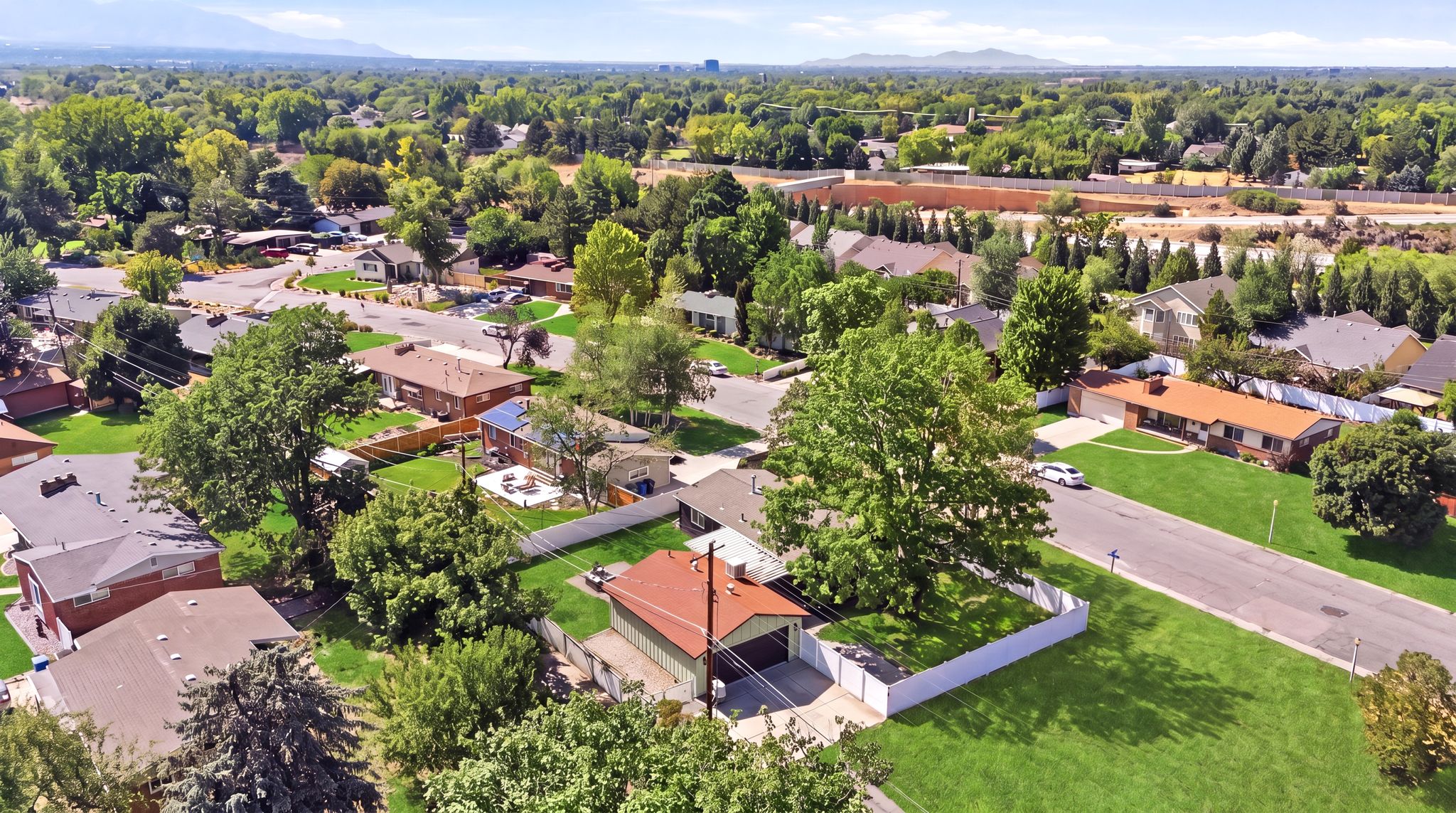 Expansive residential neighborhood featuring lush green lawns, mature trees, and a distant mountain range backdrop