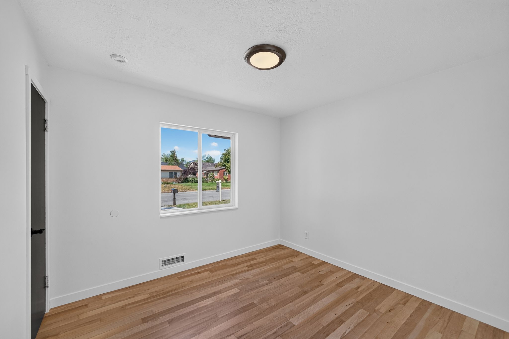 Interior room featuring light wood-finish flooring and a white baseboard trim