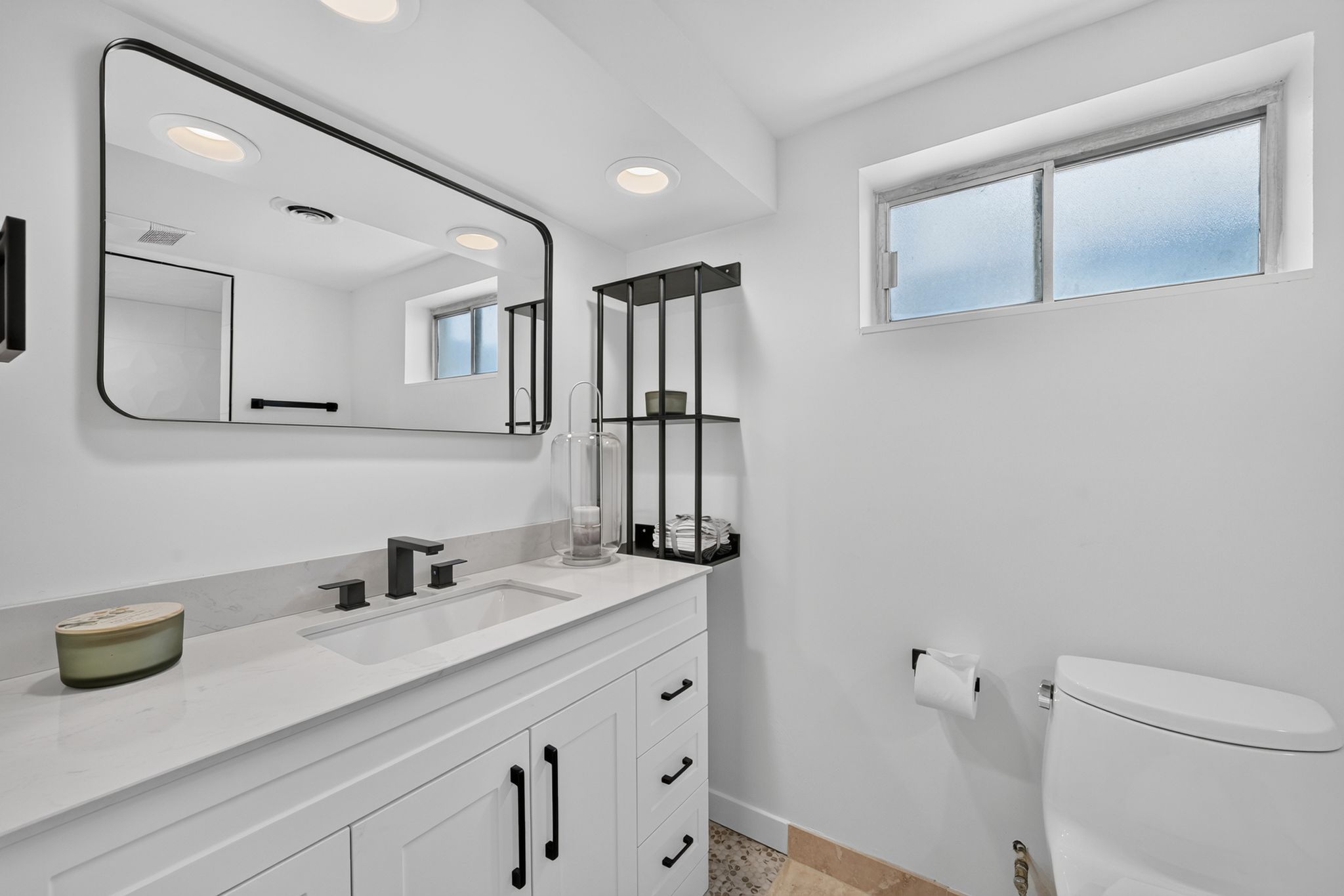 Bathroom featuring a white vanity with panel cabinetry and matte black hardware, a rectangular undermount sink with a matte black widespread faucet, and a large rectangular mirror