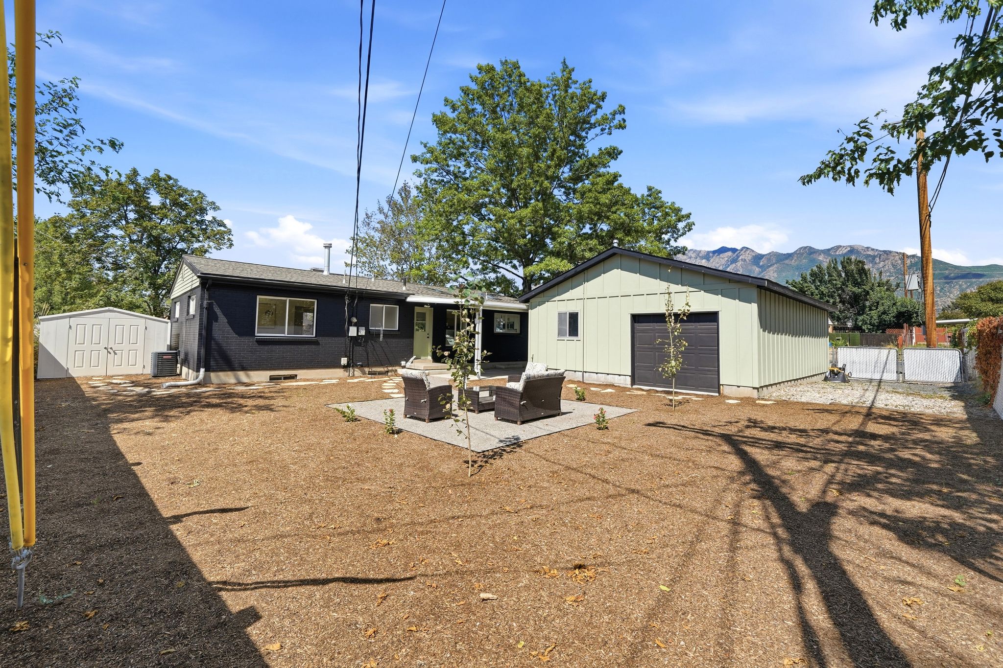 Expansive backyard featuring a large detached garage with a roll-up door, a separate storage shed, and a stone paver patio
