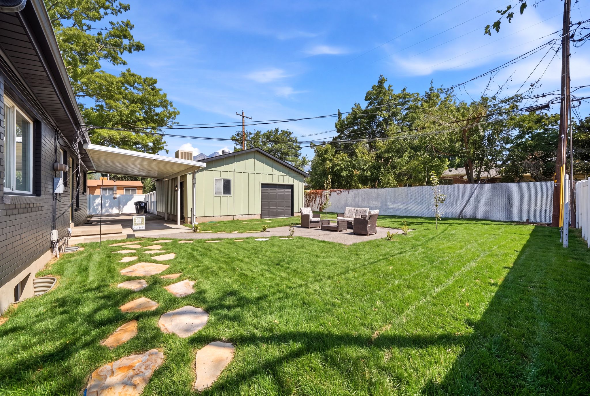 Expansive backyard featuring a lush lawn, flagstone pathway, and a patio area