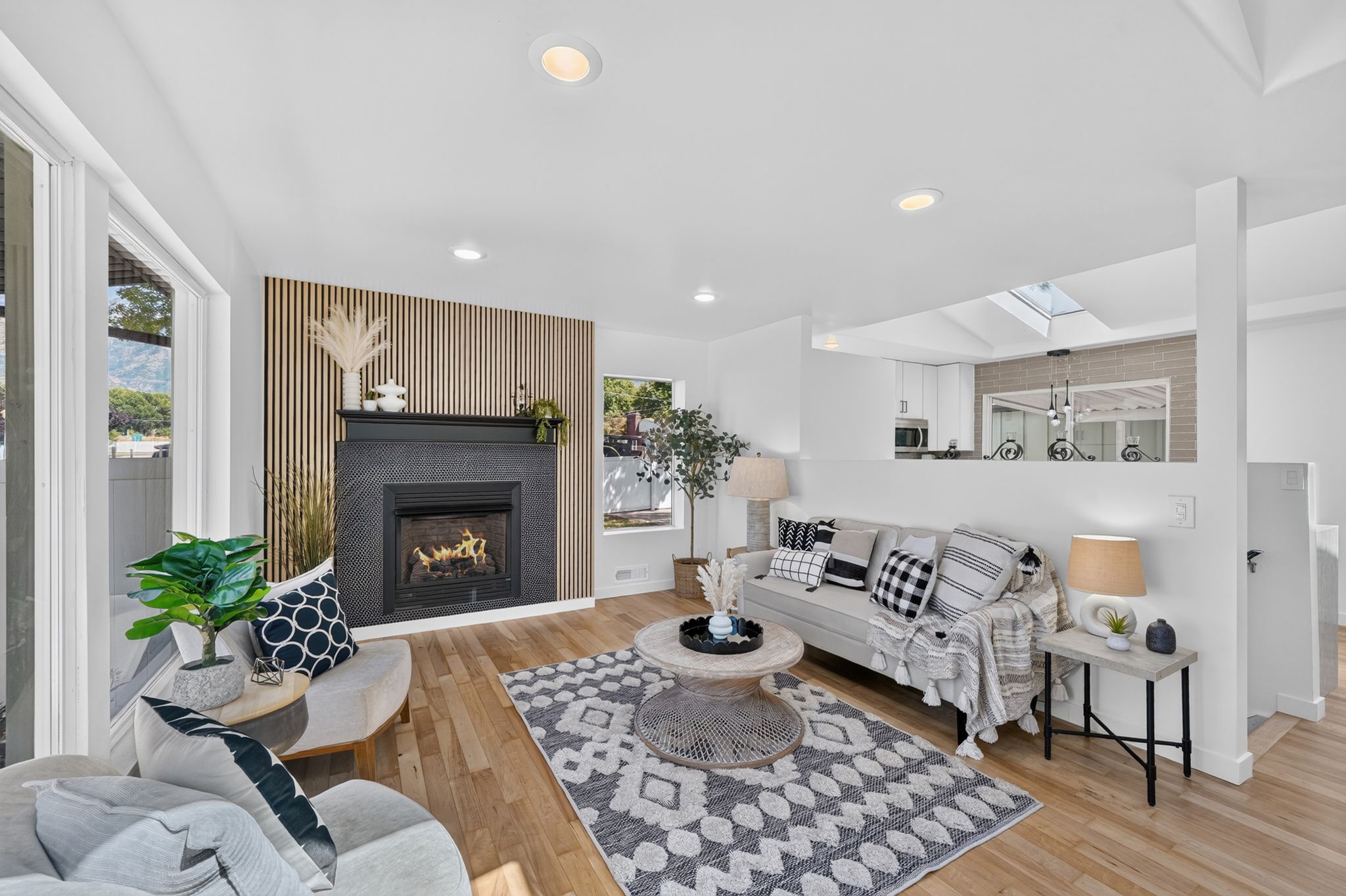 Living area featuring wood-finish flooring, a contemporary fireplace with a dark stone surround, and an accent wall with vertical slat detailing