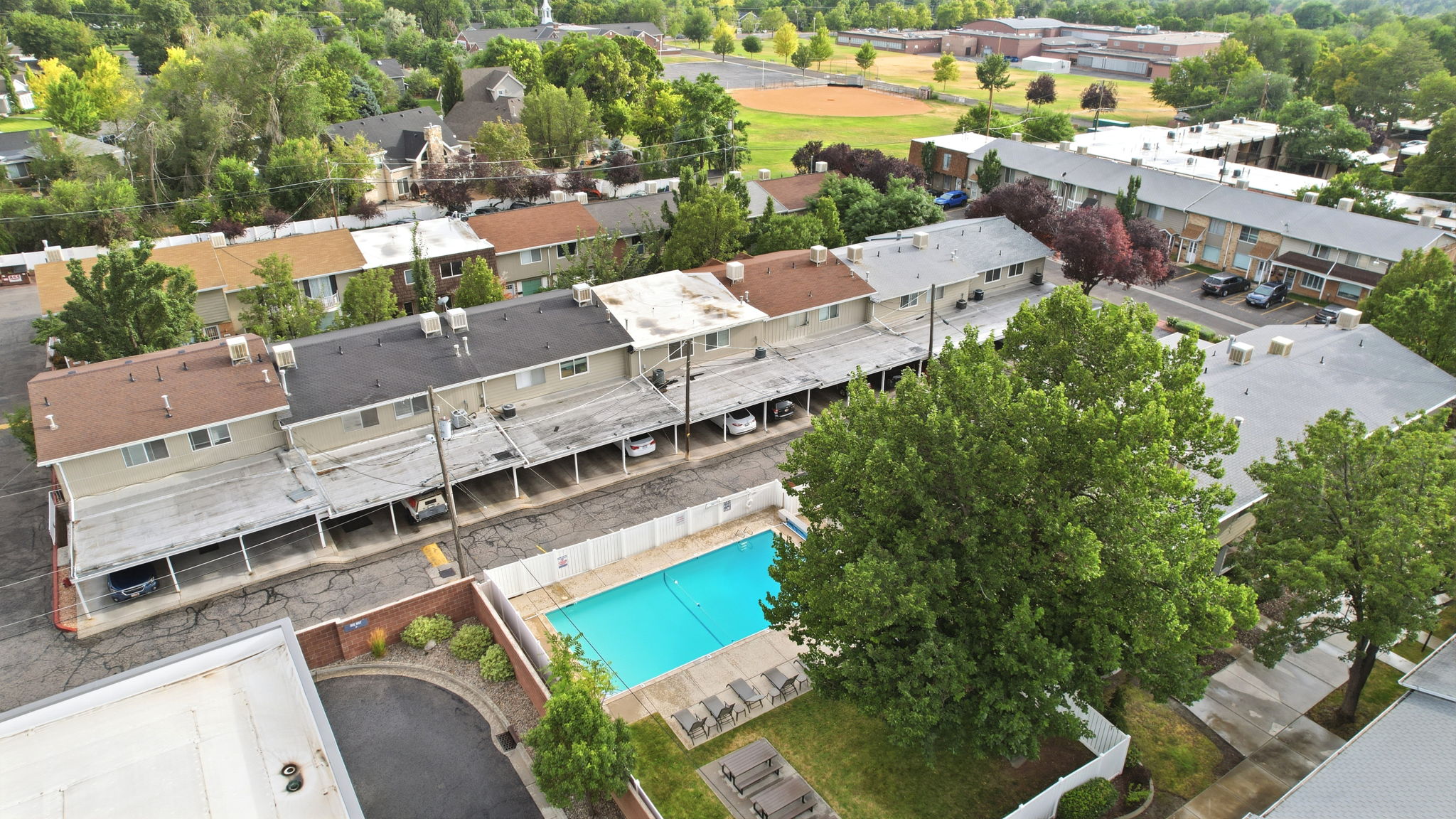 Outdoor swimming pool with surrounding patio space and green lawn area. Picnic table and clubhouse.
