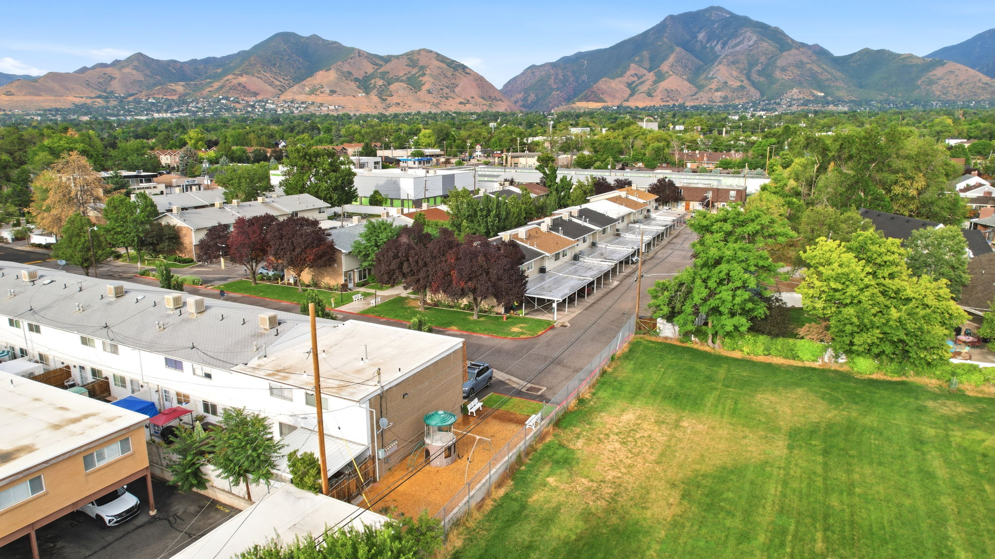 Aerial perspective showcasing multiple two-story residential buildings with flat roofs and a backdrop of verdant mountains