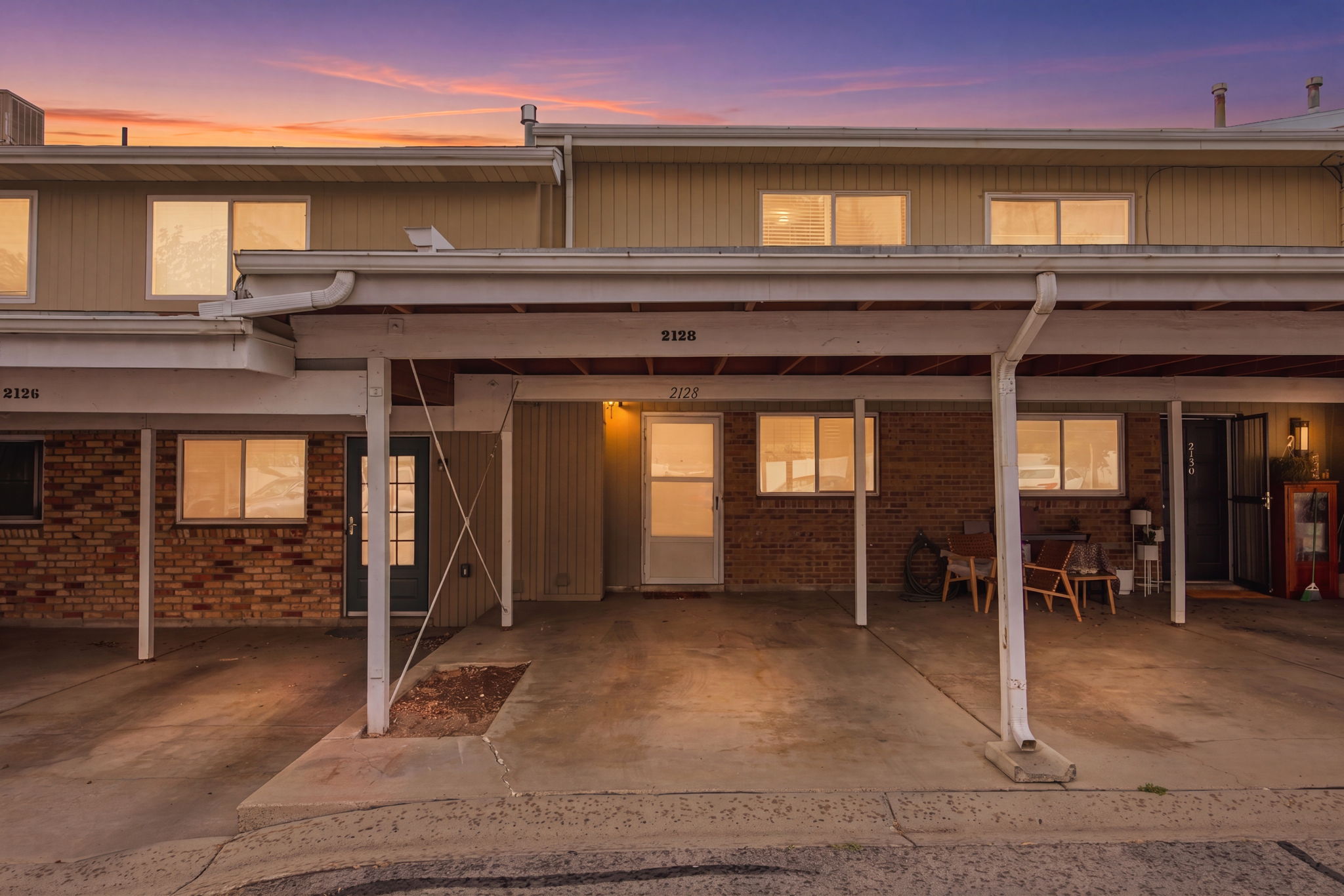 Multi-unit residential exterior featuring brick and siding facades, individual entry doors, and ground-level windows. This unit has 2 covered parking stalls. Most units only have 1.
