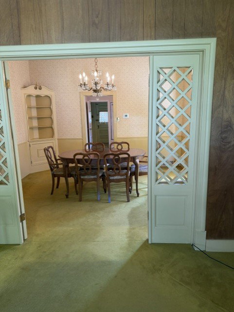Dining room featuring a chandelier, built-in corner hutch, wallpapered walls, and carpet flooring
