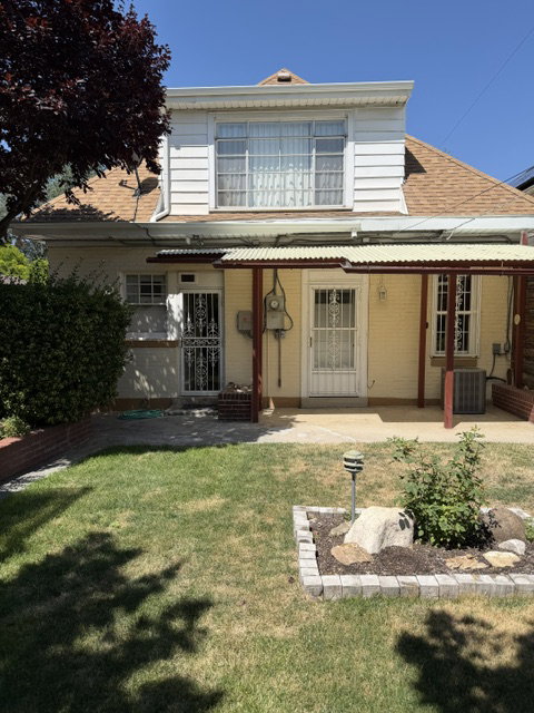 Rear exterior featuring a covered patio, two entry doors with security screens, and a second-story window dormer