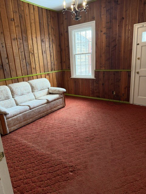 Main level bedroom with outside entrance or could be used for an extra gathering room with outside extrance.Wood paneling throughout this room, featuring a white window frame and an ornate chandelier