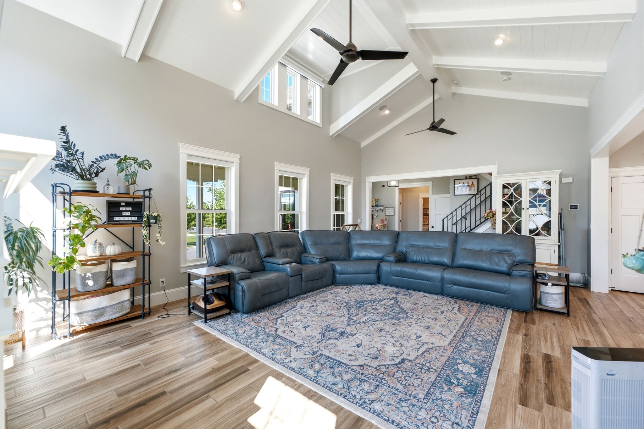 Spacious living area featuring vaulted ceilings with exposed beams, multiple windows providing ample natural light