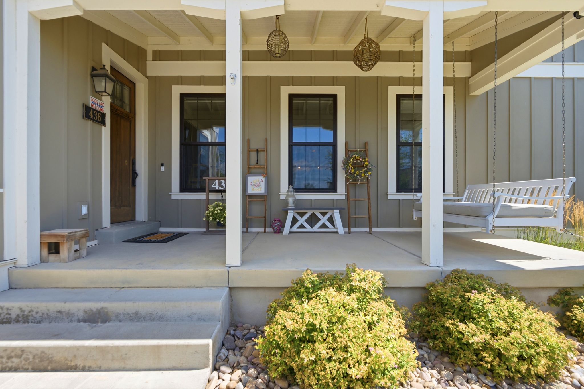 Inviting covered front porch with a wood-finish entry door and board-and-batten siding