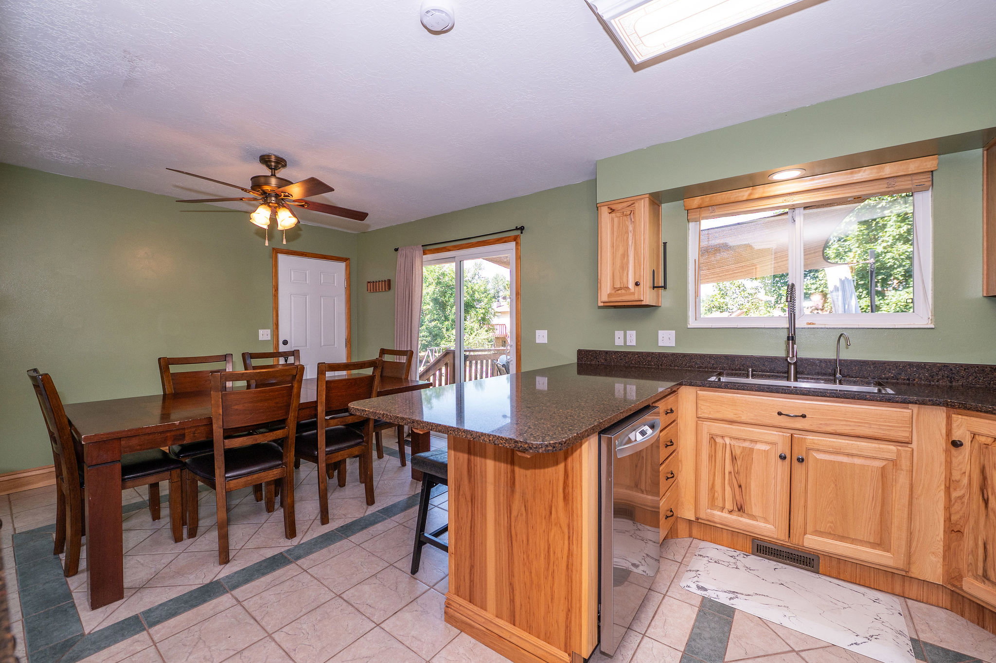 Kitchen featuring light wood cabinetry, dark countertops, and a stainless steel dishwasher