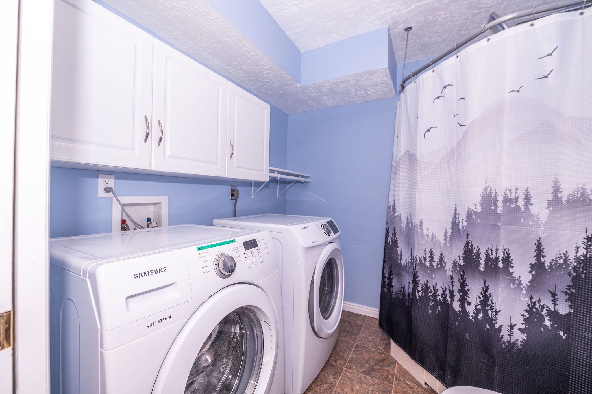 Laundry area featuring white cabinetry, a built-in shelf, and tiled flooring