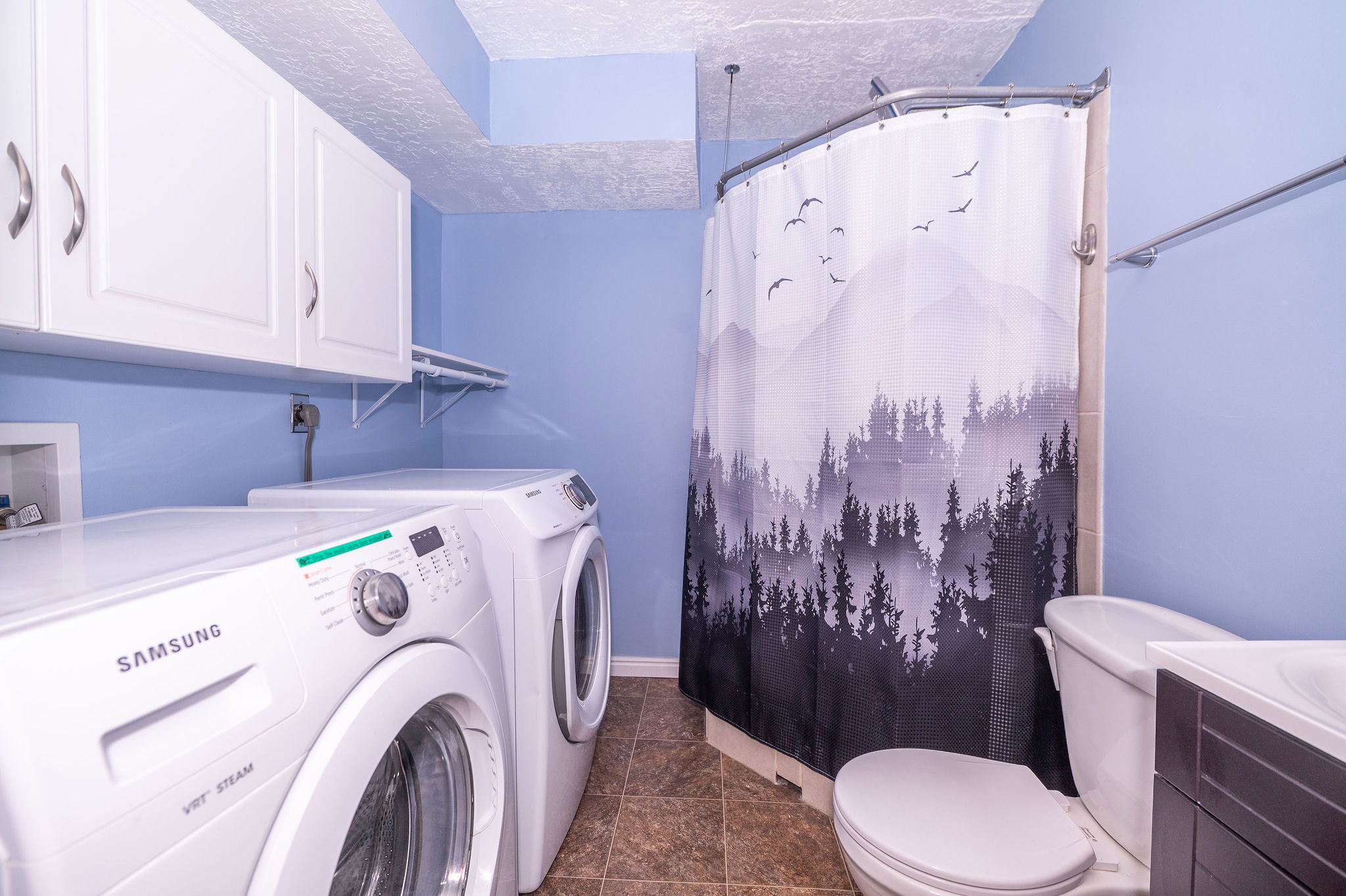Dedicated laundry area featuring white upper cabinetry, a utility shelf, and tile-finish flooring