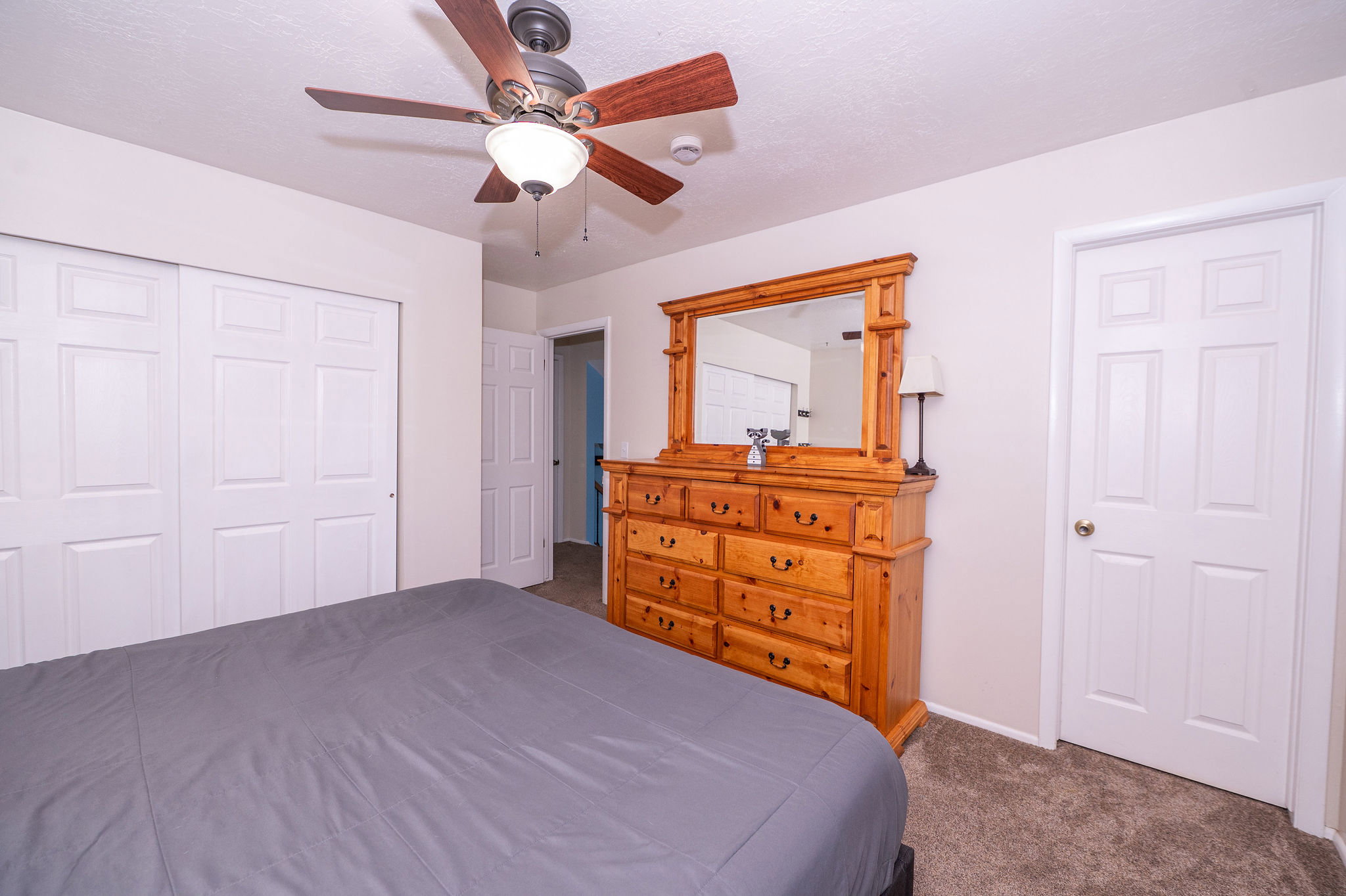 Carpeted bedroom with a ceiling fan light fixture
