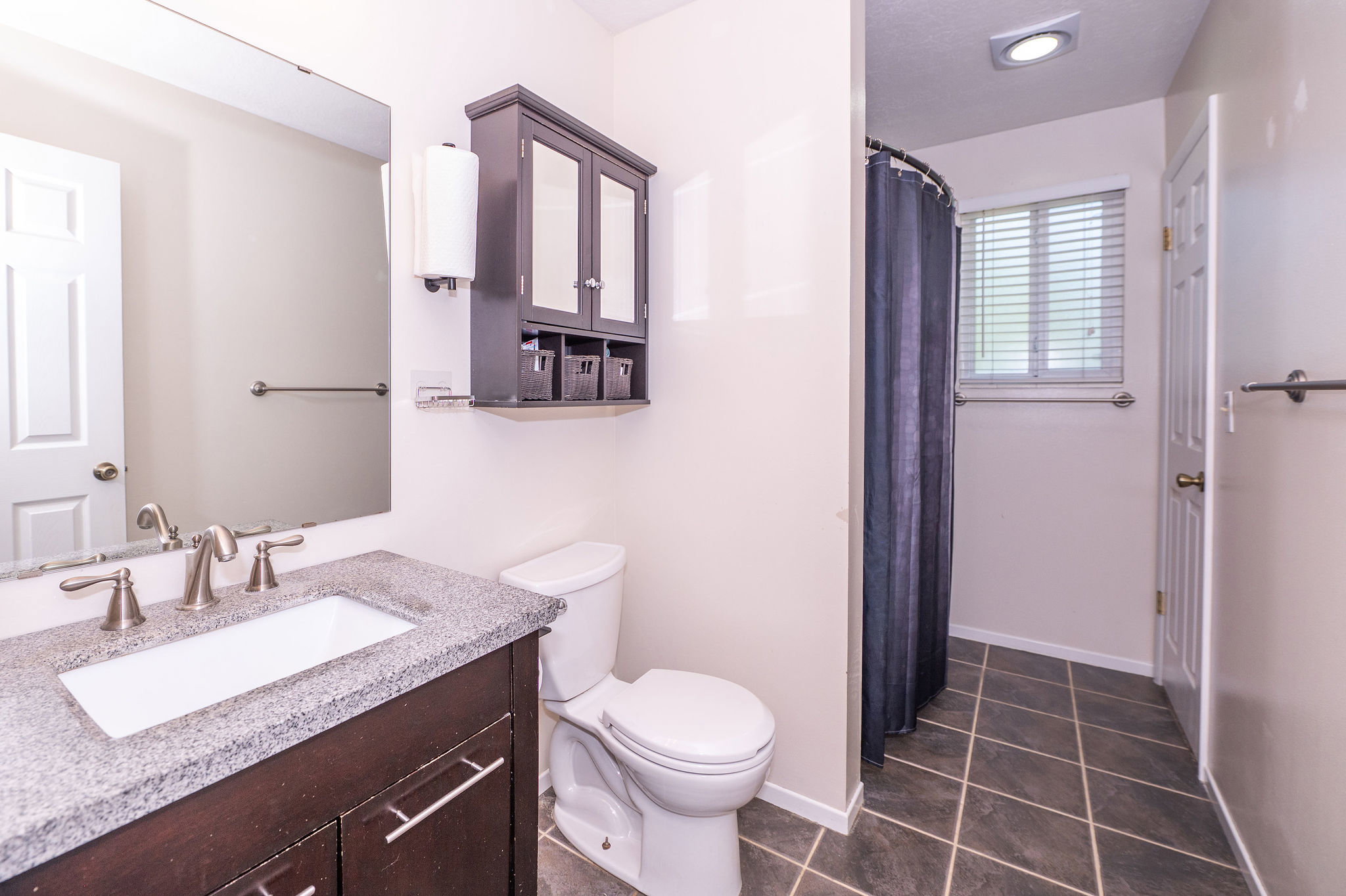 Bathroom featuring a dark wood-finish vanity with a light speckled countertop, an undermount sink, and brushed nickel fixtures