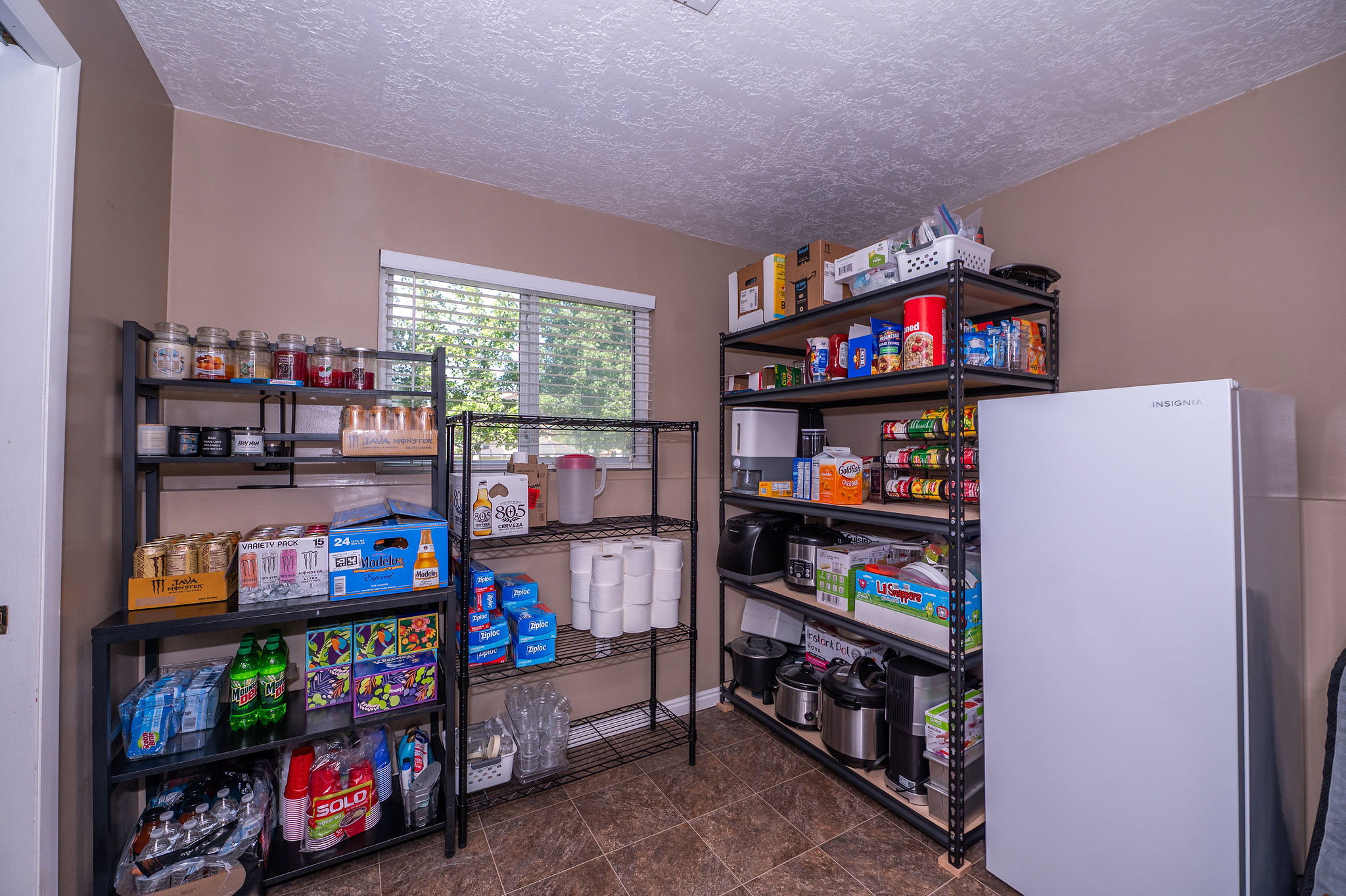 Dedicated pantry space featuring durable wire shelving, a window with blinds, and tiled flooring