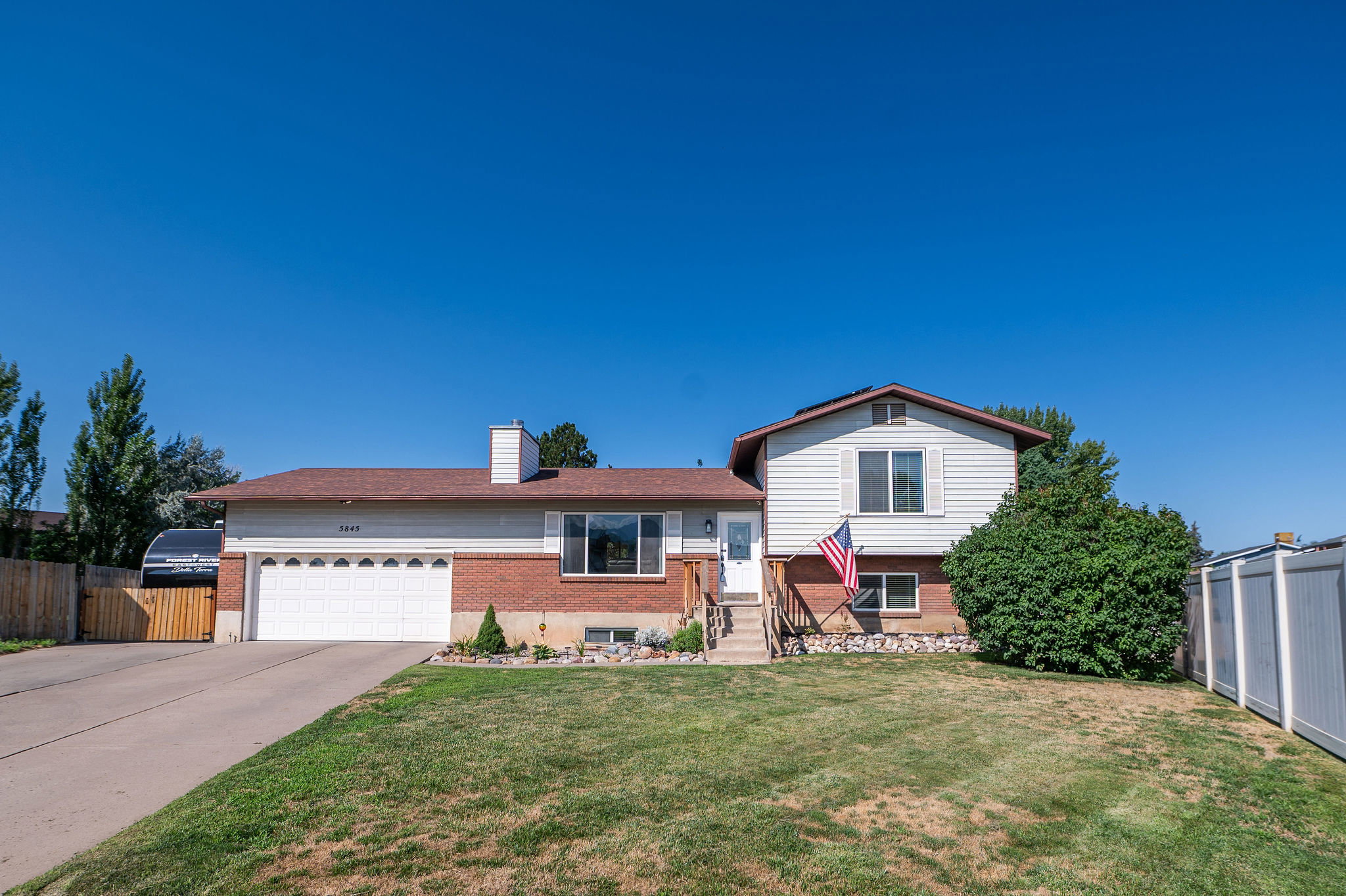 Split-level residence featuring a brick and siding facade, attached two-car garage, and a concrete driveway