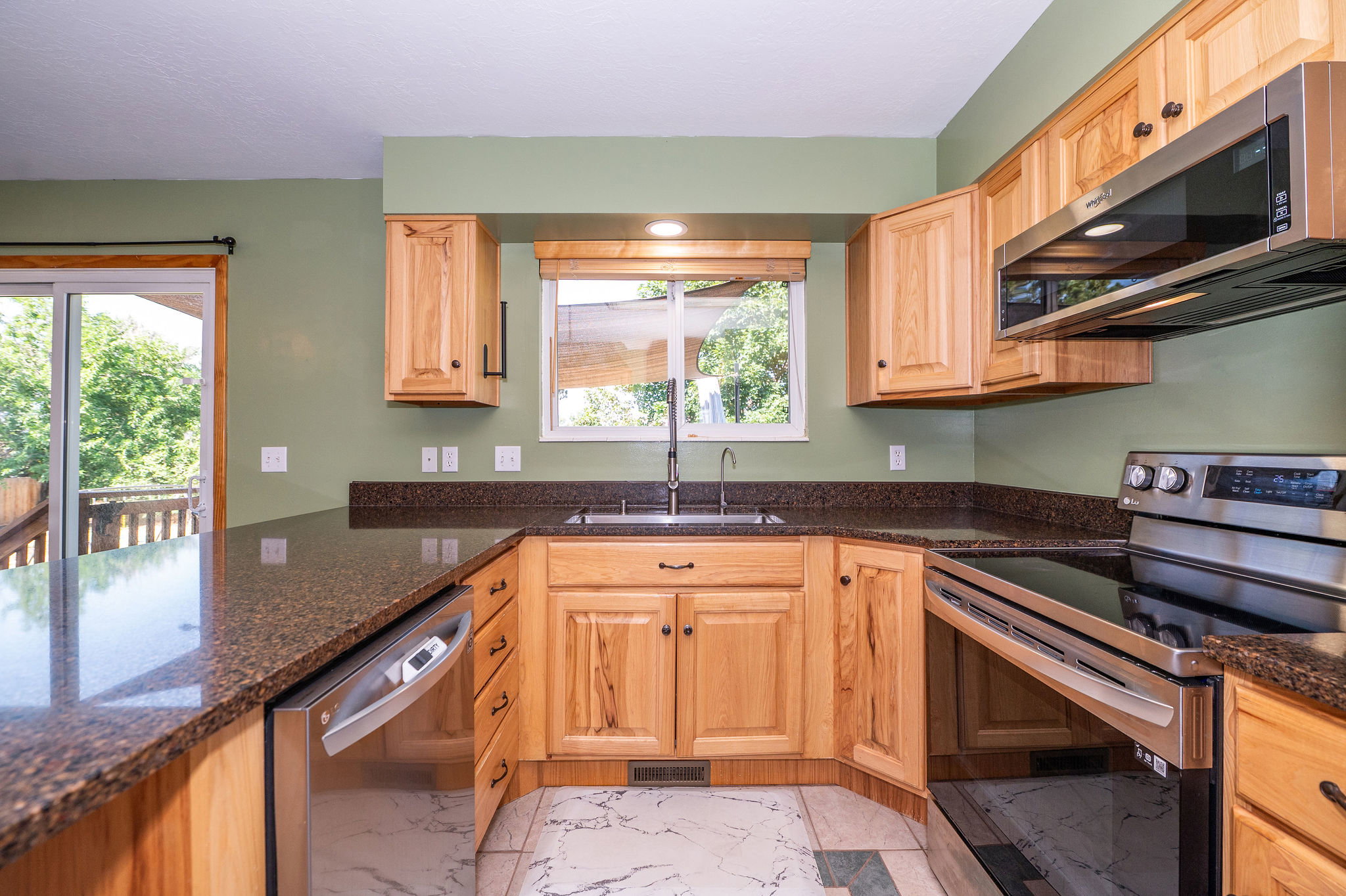 Kitchen featuring wood cabinetry, dark speckled countertops, stainless steel appliances, and a tile floor