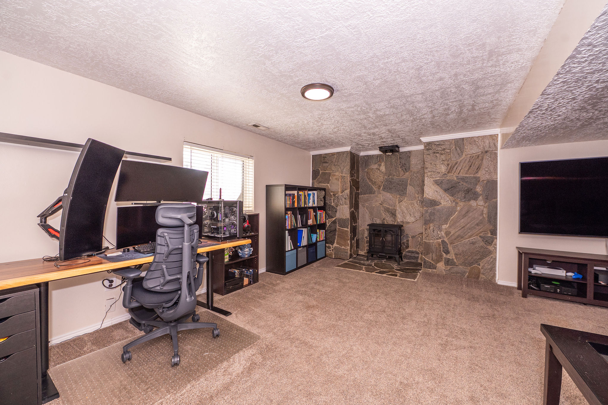 Room featuring a stone fireplace with a black wood-burning stove insert